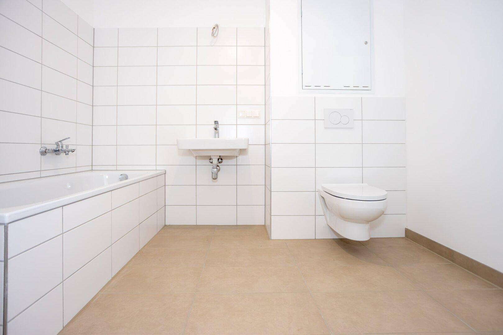 Modernes Badezimmer mit Badewanne, wandhängendem WC und Einzelwaschbecken.