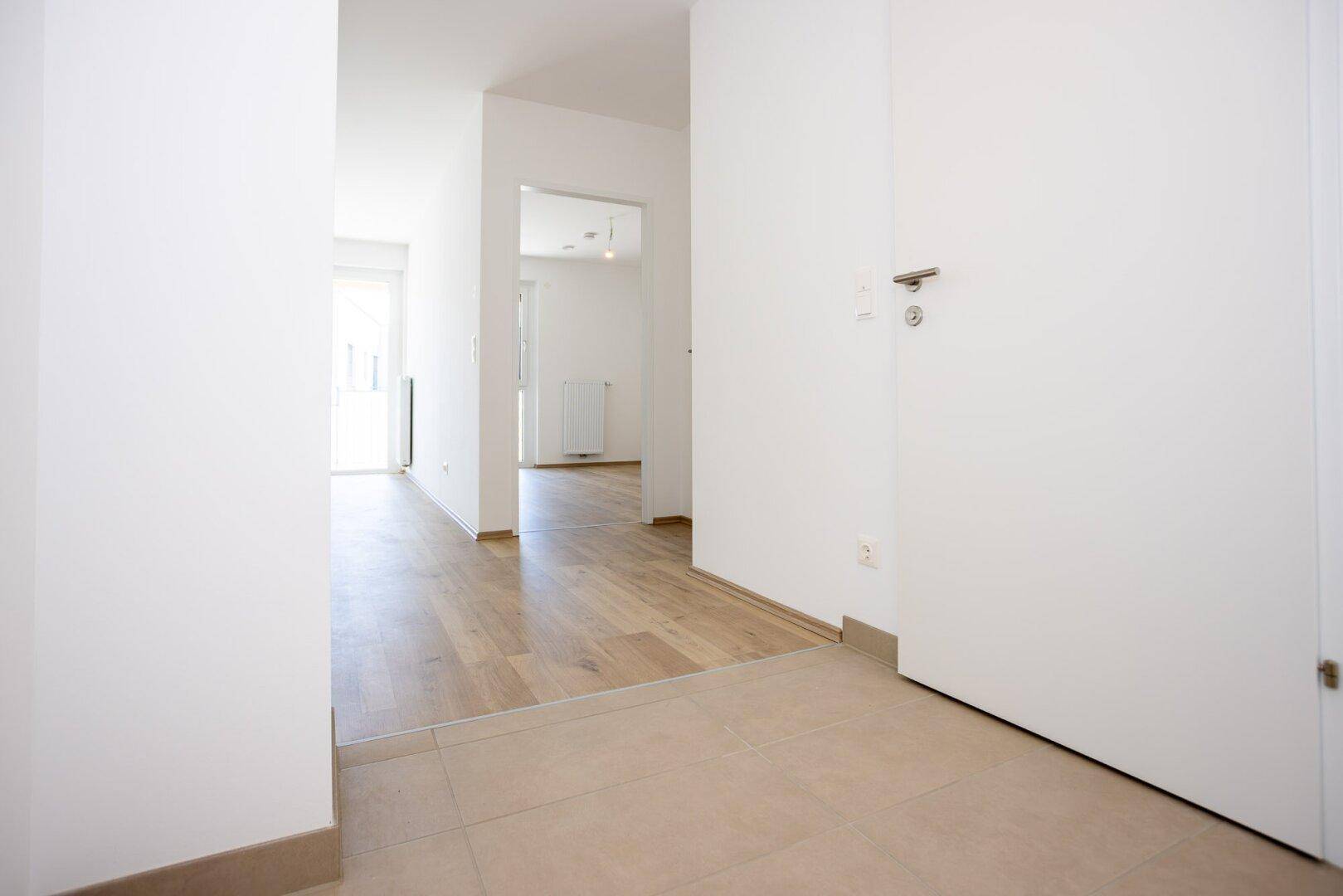 Heller Flur mit Fliesenboden, der zu den anderen Räumen der Wohnung führt.