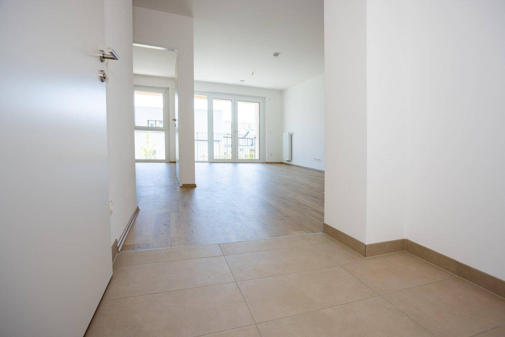 Heller Eingangsbereich mit Fliesenboden, der in den Wohnbereich mit Laminat übergeht.