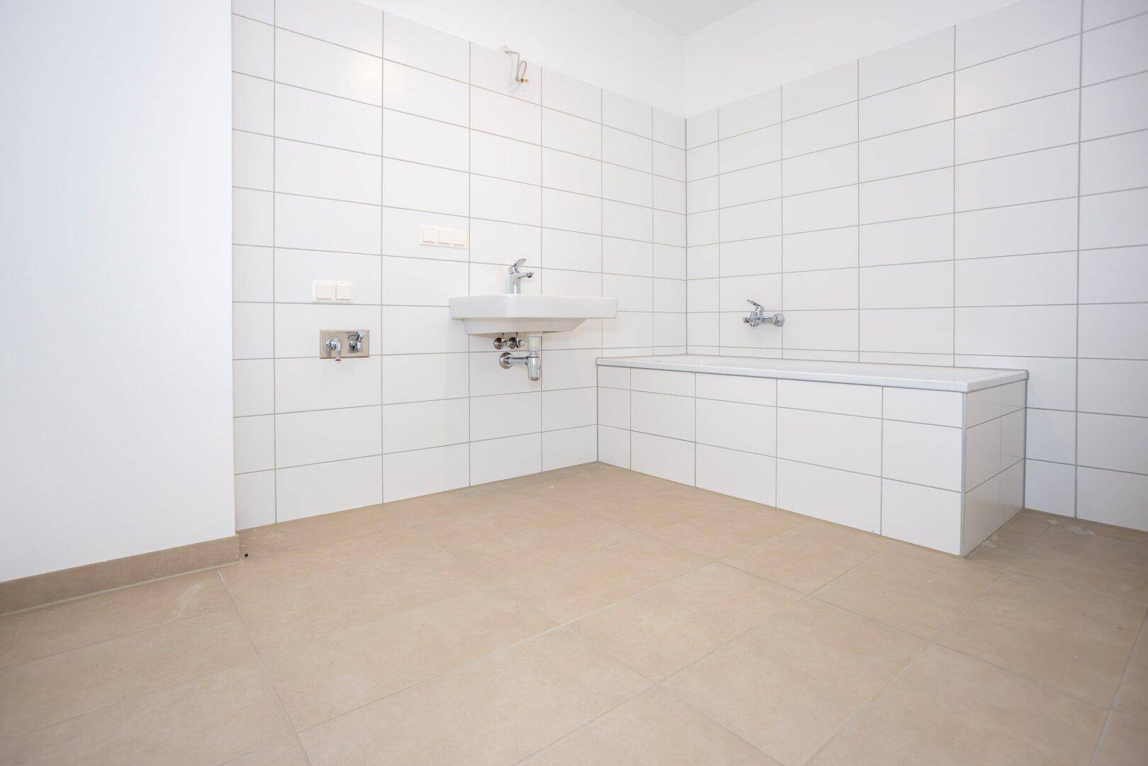 Modernes Badezimmer mit weißen Wandfliesen, beigefarbenem Boden und eingebauter Badewanne.