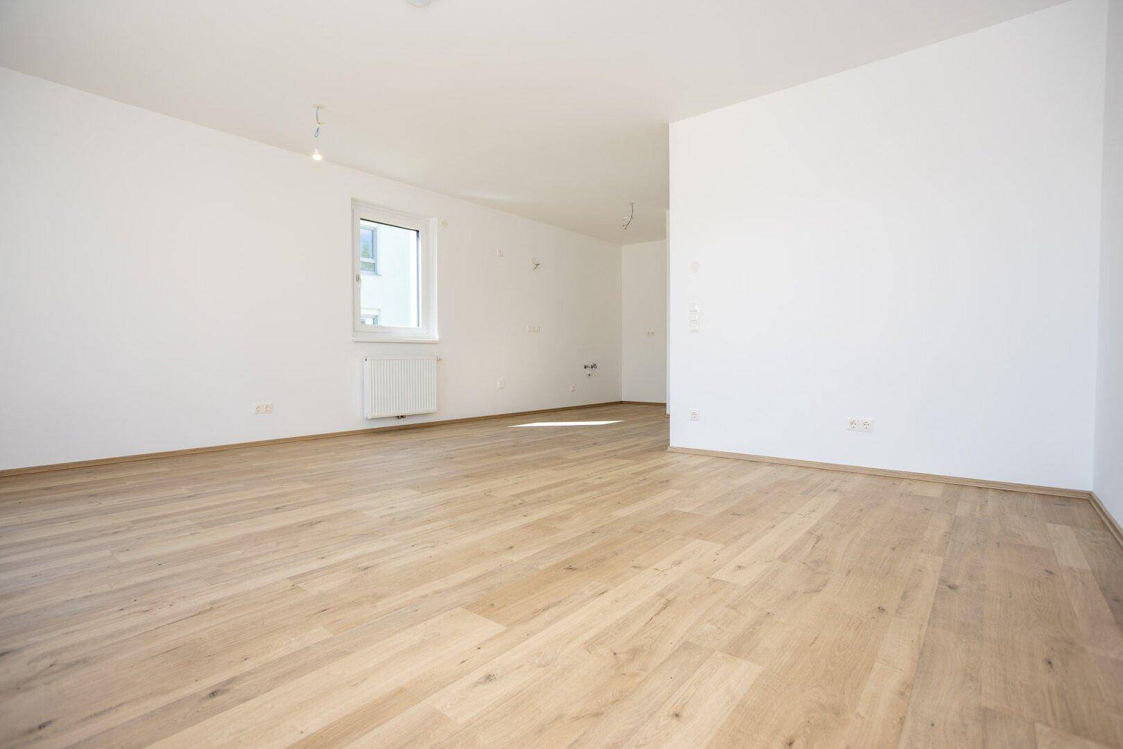 Heller Raum mit Laminatboden, weißen Wänden und einem Fenster, bereit zur individuellen Gestaltung.