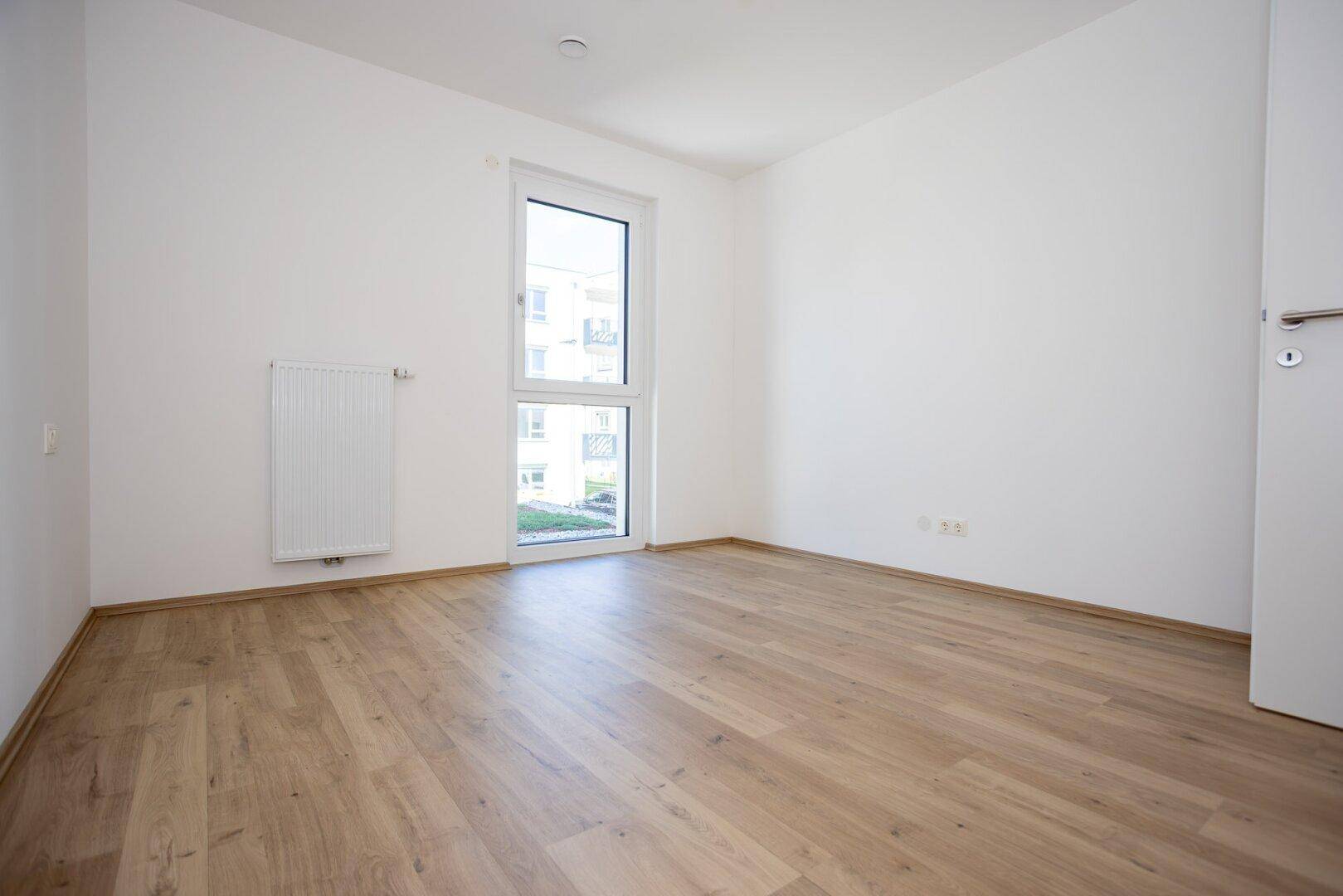 Geräumiges Schlafzimmer mit hellem Laminatboden und weißen Wänden, ideal für individuelle Gestaltung.