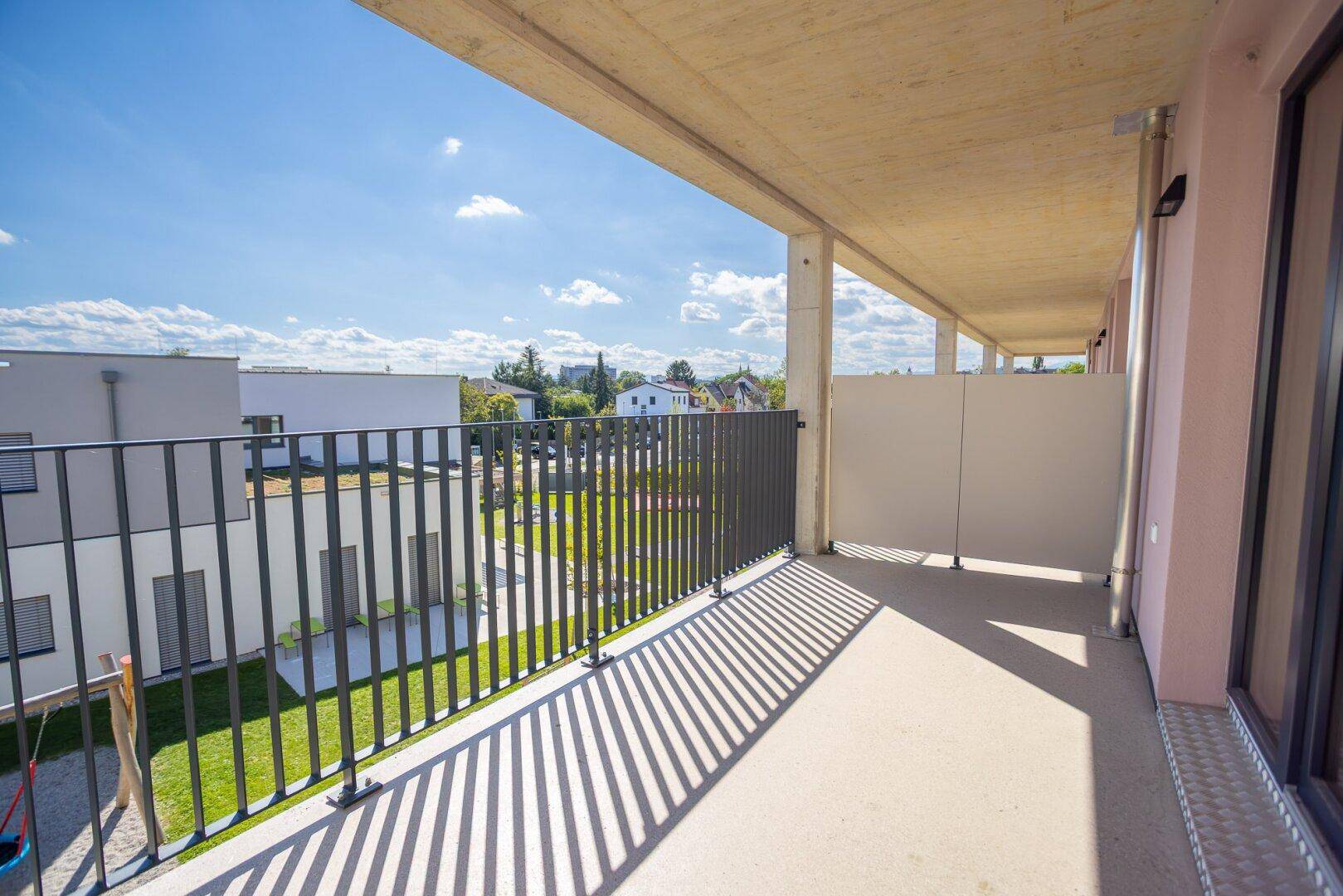 Heller Balkon mit Blick auf die grüne Umgebung und die modernen Wohngebäude.