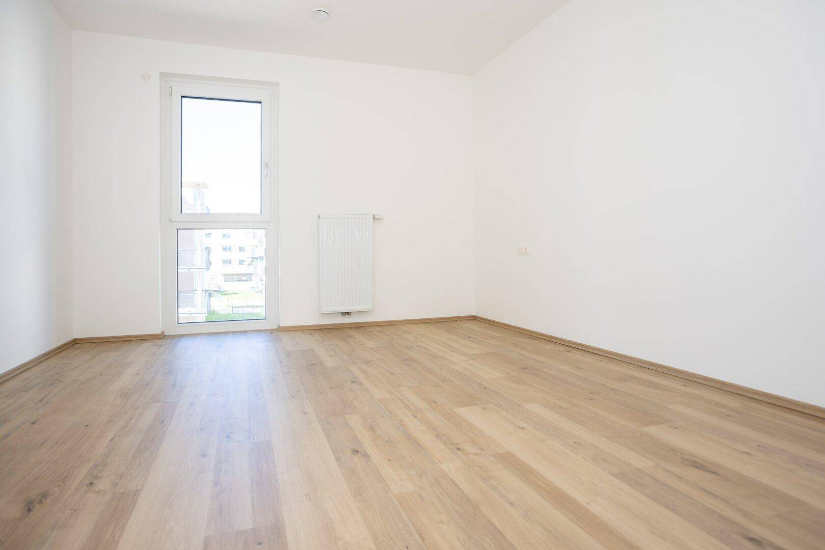 Heller Raum mit Laminatboden und Fenster, ideal als Schlaf- oder Arbeitszimmer.