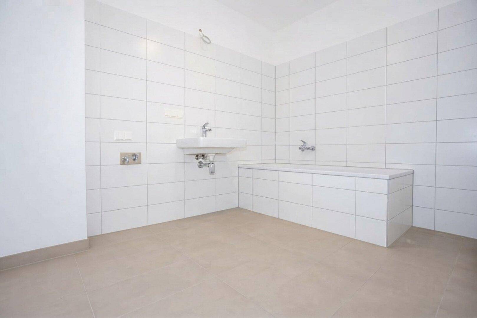 Modernes Badezimmer mit weißen Fliesen, integrierter Badewanne und Einzelwaschbecken.