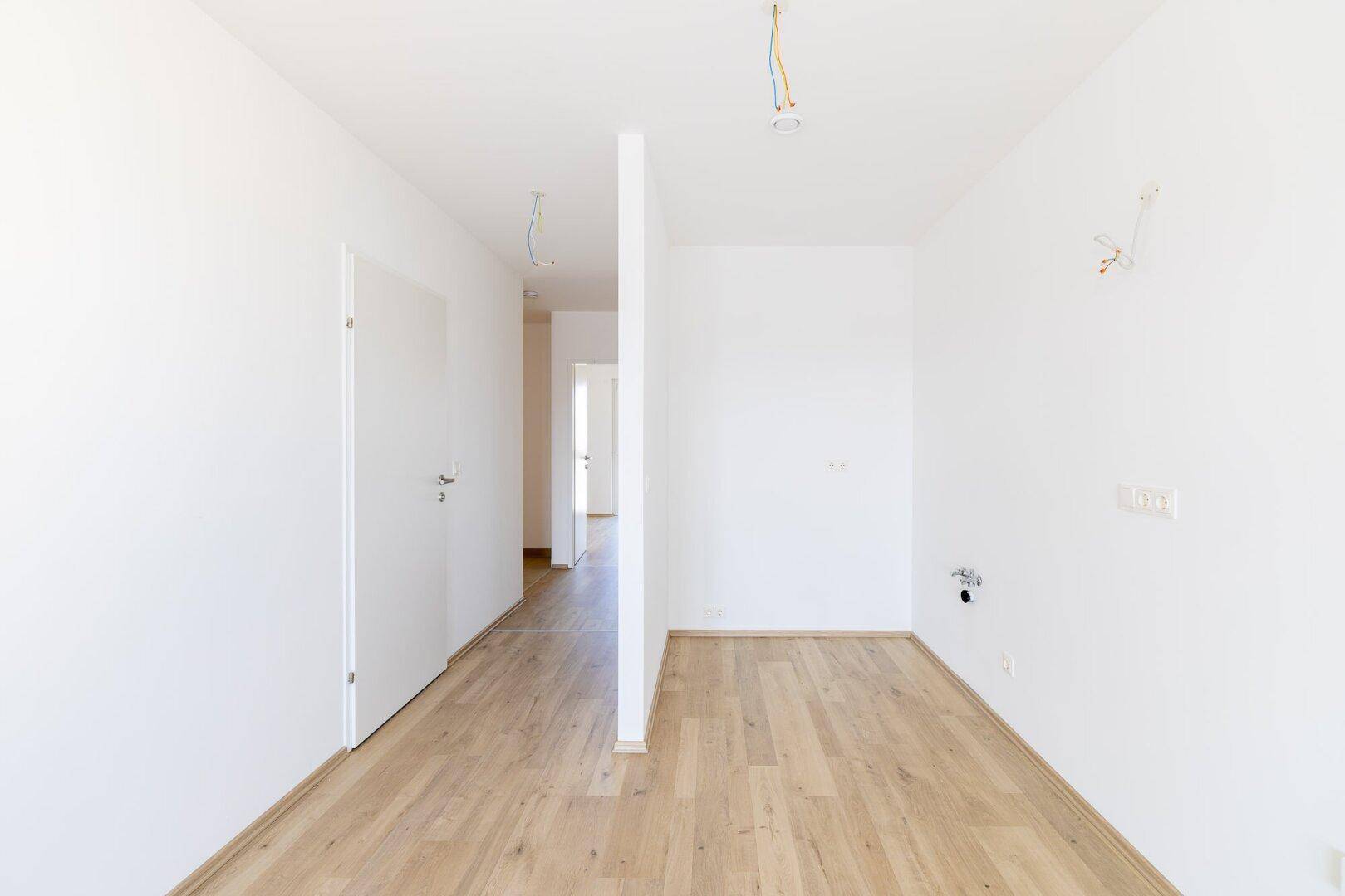 Heller Flur mit Laminatboden und weißen Türen, der zu weiteren Räumen führt.