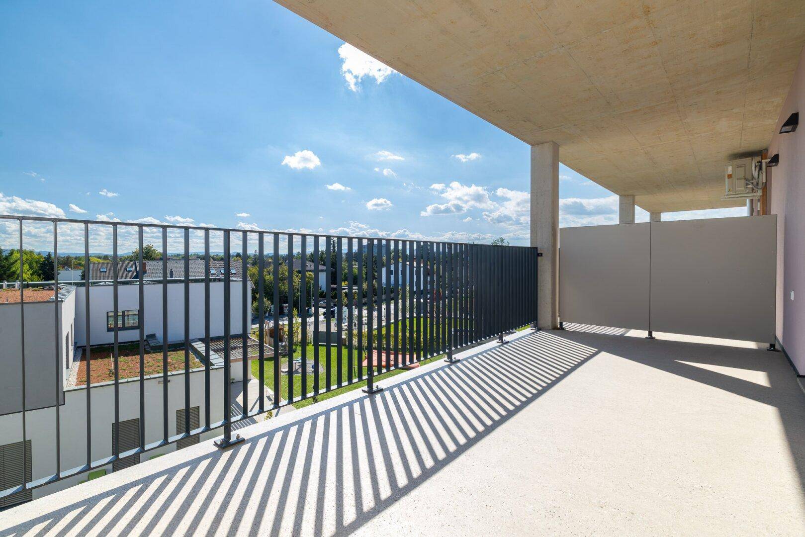 Sonniger Balkon mit schattenspendendem Überstand und Blick auf die umliegenden Gebäude.
