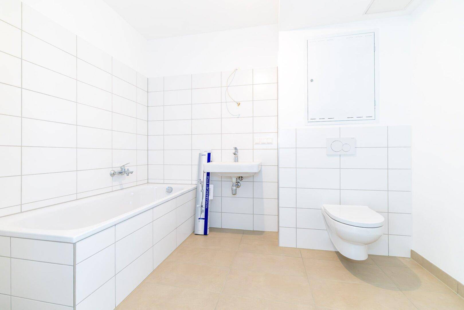 Modernes Badezimmer mit Badewanne, Waschbecken und Wand-WC, hell gefliest.
