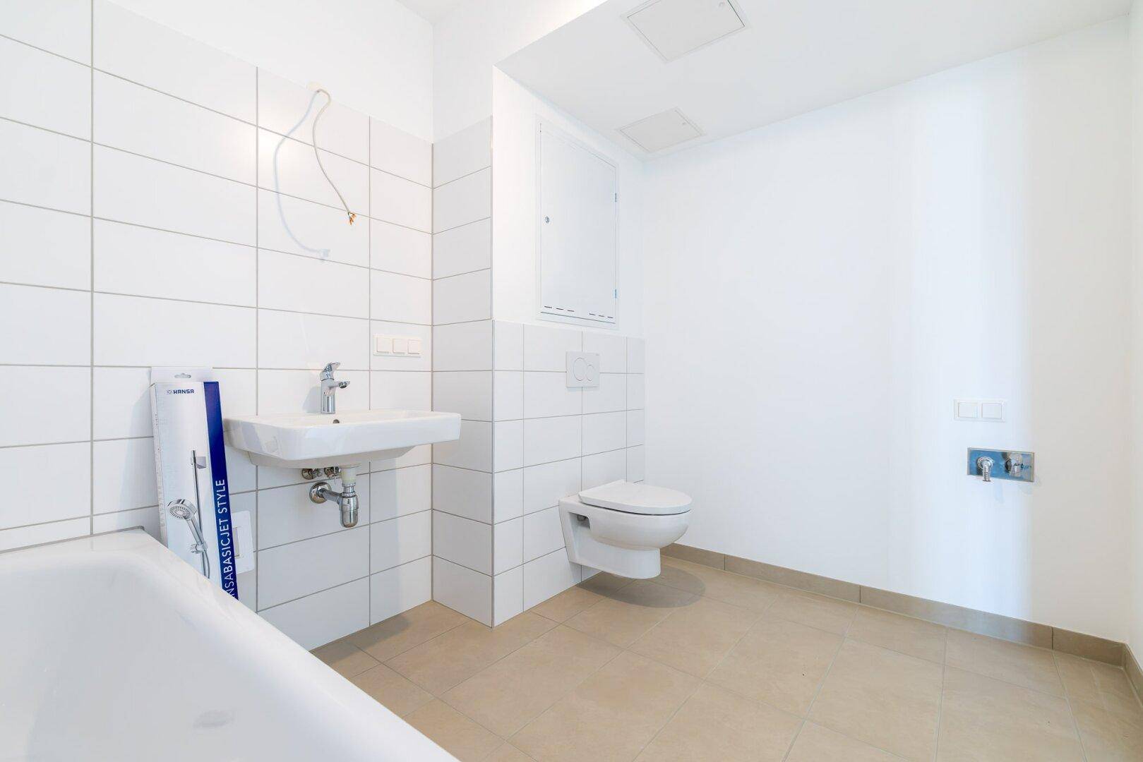 Modernes Badezimmer mit Badewanne, Waschbecken und Wand-WC in neutralen Farben.