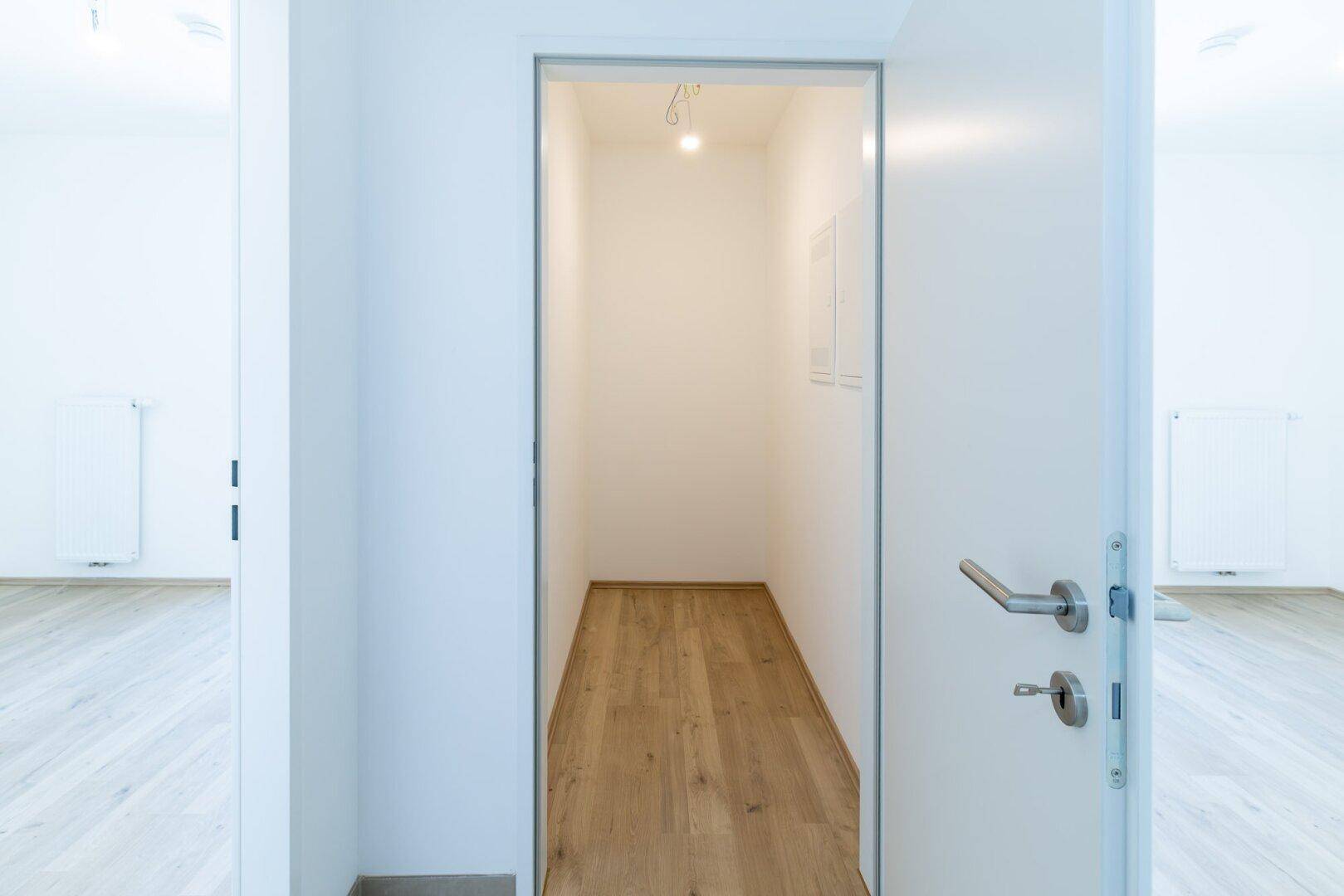 Schmaler Abstellraum mit Laminatboden und weiß gestrichenen Wänden, ideal für Lagerung.