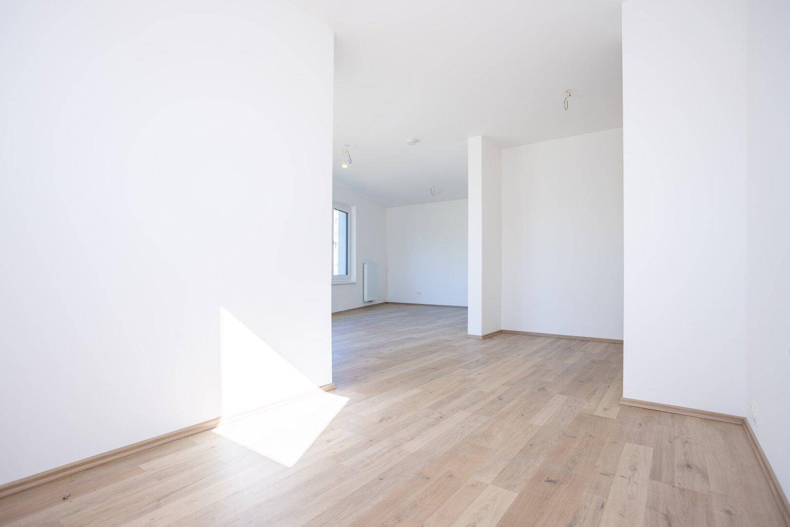 Heller Flurbereich mit Laminatboden und weißen Wänden, der zu weiteren Räumen führt.