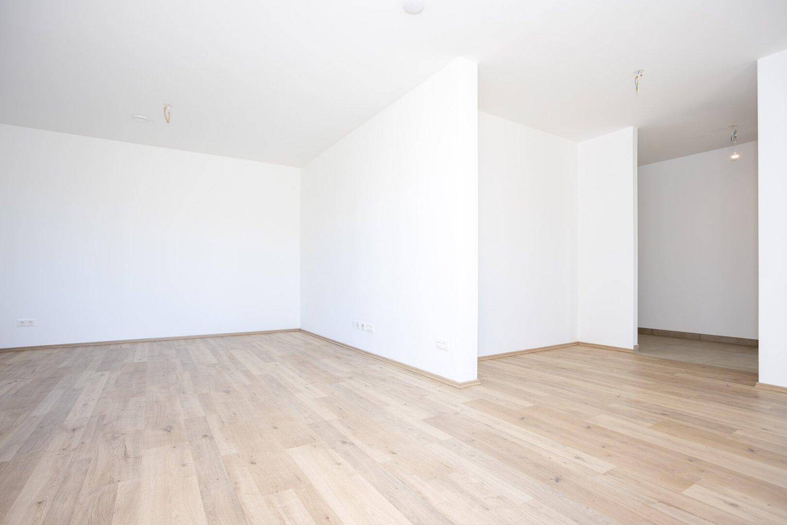 Heller, leerer Innenraum mit Laminatboden und weißen Wänden, ideal für individuelle Gestaltung.