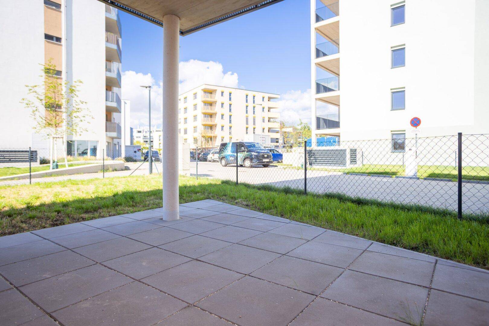 Gepflasterte Terrasse im Freien mit Blick auf die umliegenden Neubauten und Grünflächen.