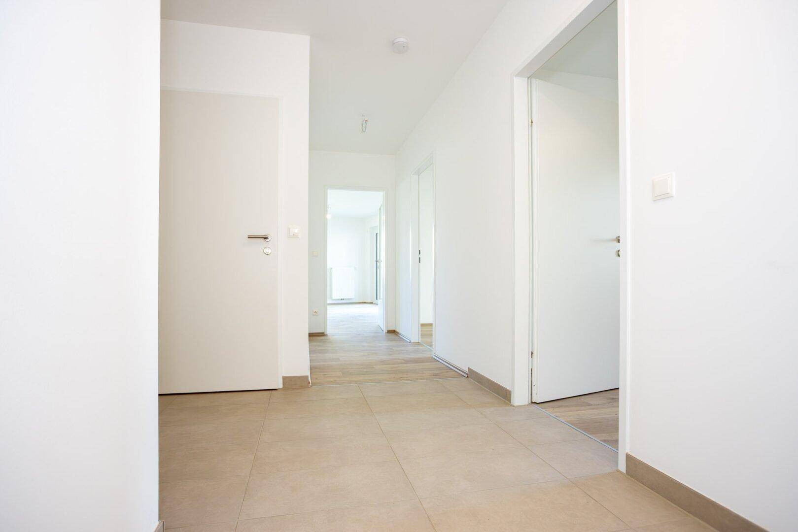 Heller Flur mit Fliesenboden und Türen zu verschiedenen Räumen der Wohnung.