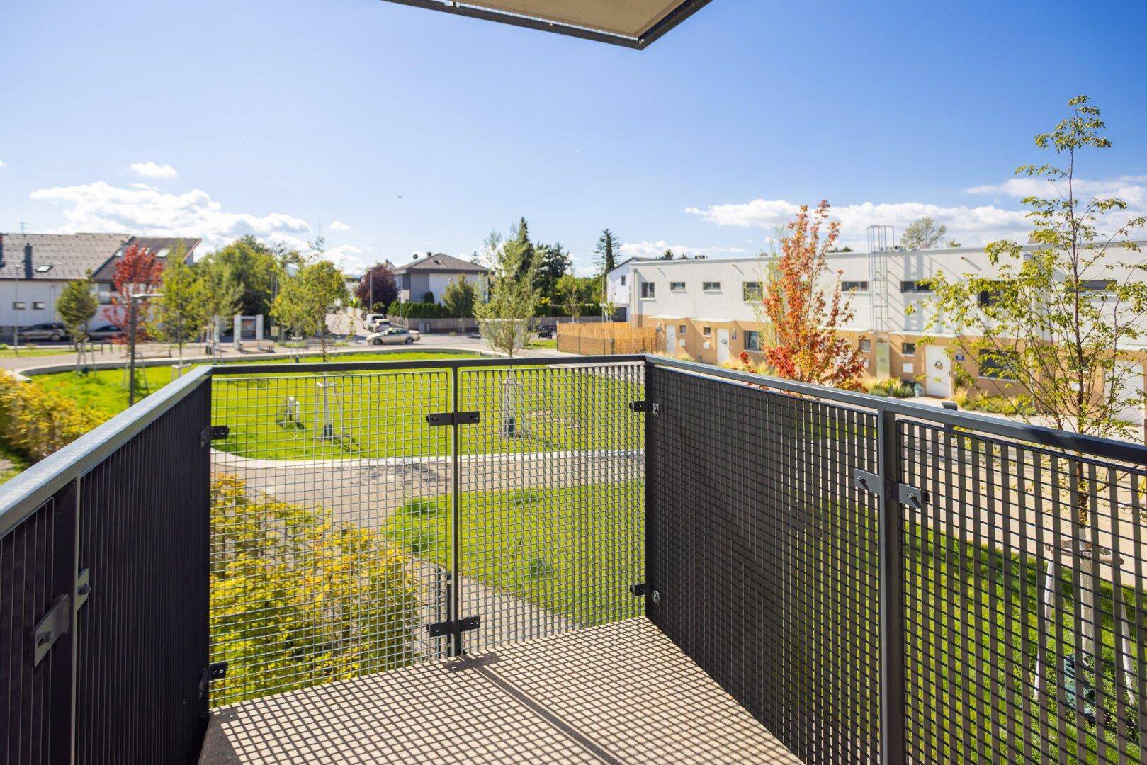 Geräumiger Balkon mit Metallgeländer und Blick auf die umliegende Wohnsiedlung.
