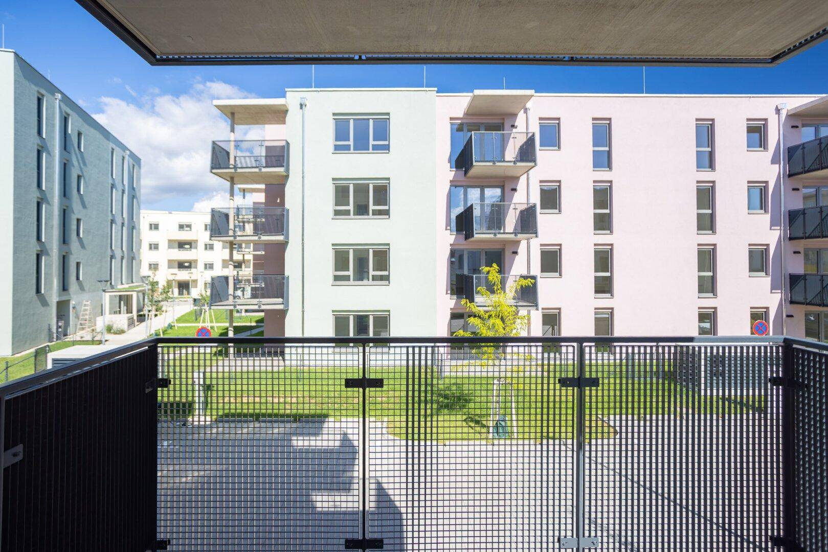 Blick vom Balkon auf die modernen Wohngebäude und die grüne Umgebung der Anlage.