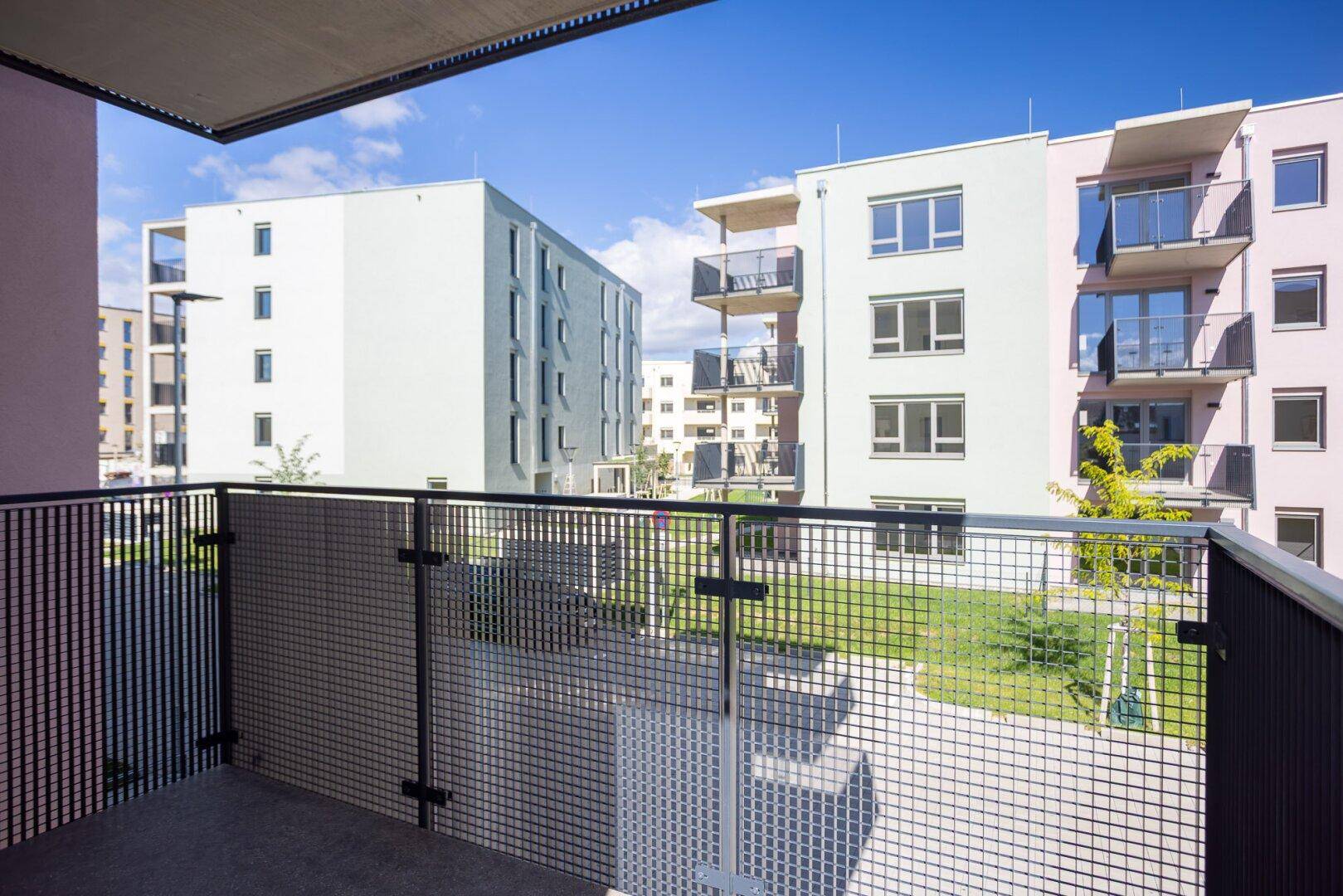 Weiter Blick vom Balkon auf die moderne Wohnanlage und die umliegenden Gebäude.