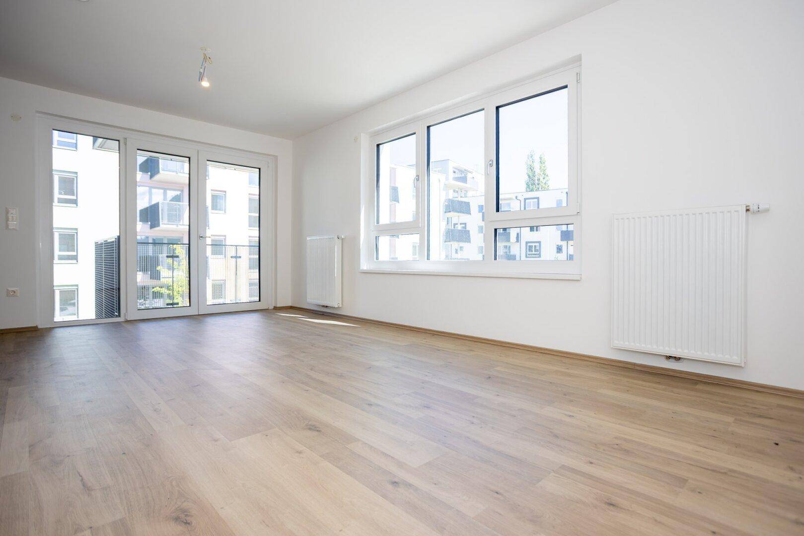 Heller Wohnbereich mit großen Fenstern und Zugang zu einem Außenbereich, ideal für Tageslicht.