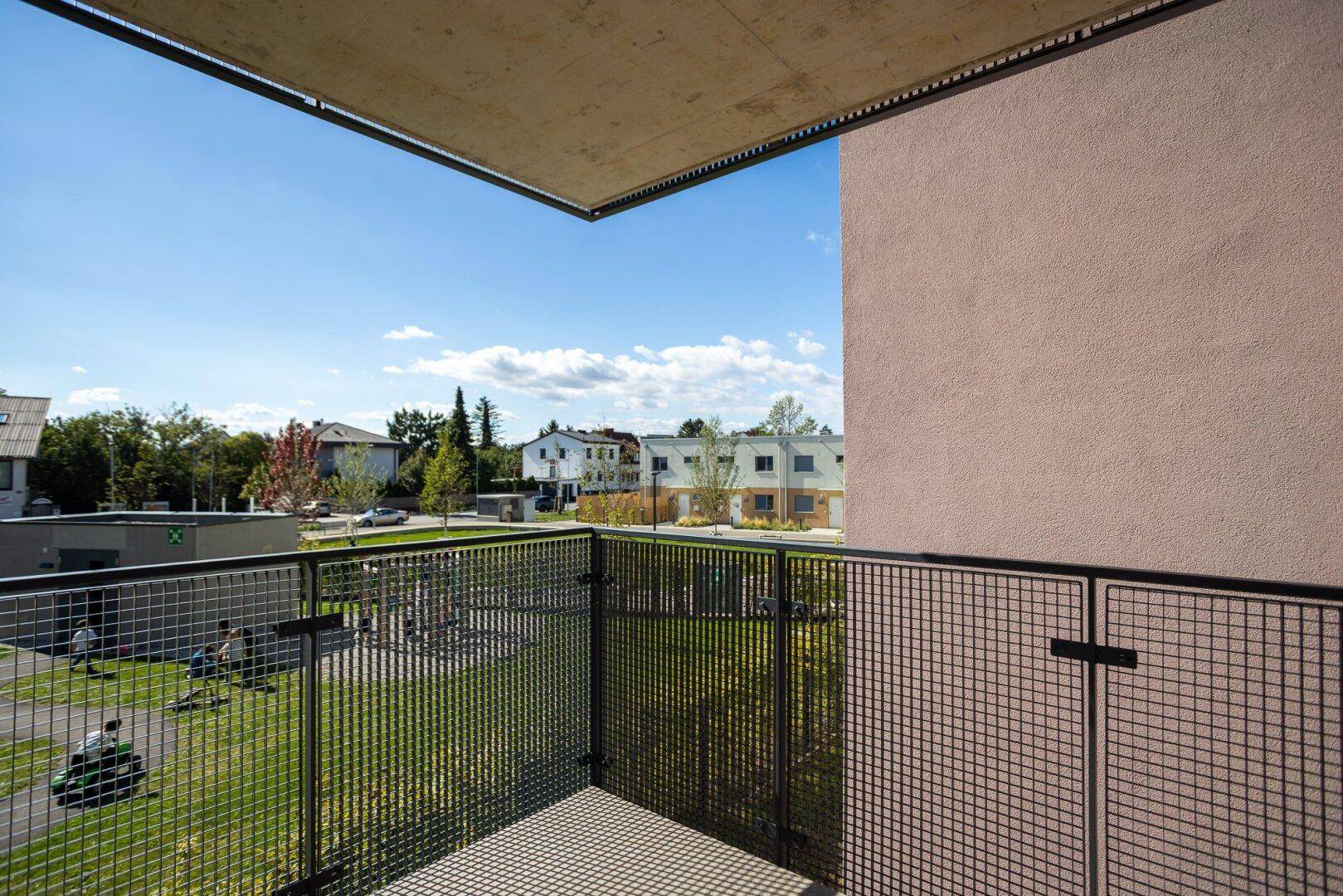 Geräumiger Balkon mit Metallgeländer und weitem Blick ins Grüne.