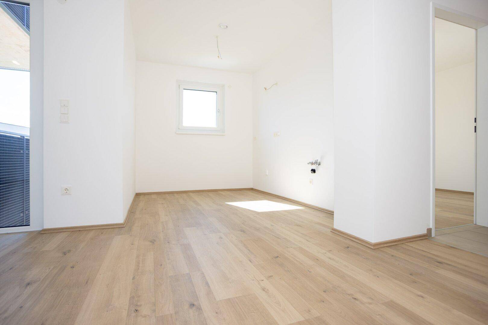 Heller Raum mit Laminatboden und einem Fenster, vorbereitet für Installationen.