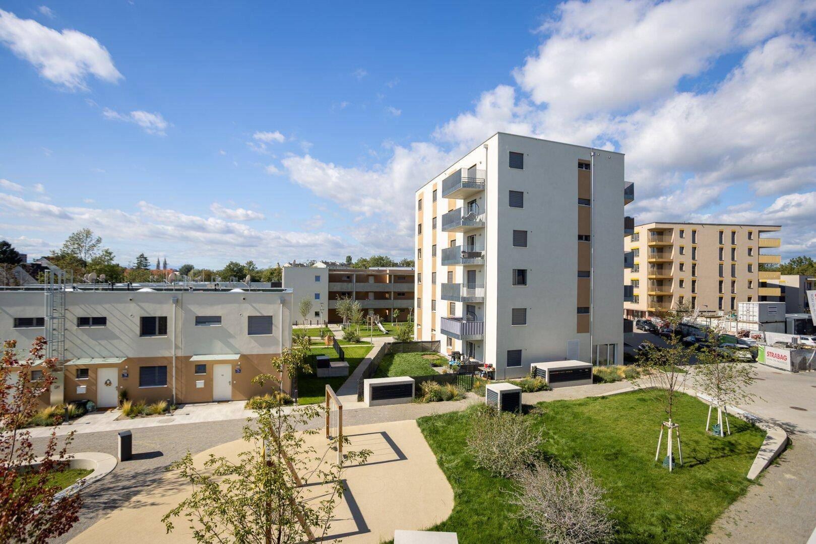 Moderne Wohngebäude in einer gepflegten Siedlung mit Grünflächen und Spielplatz.