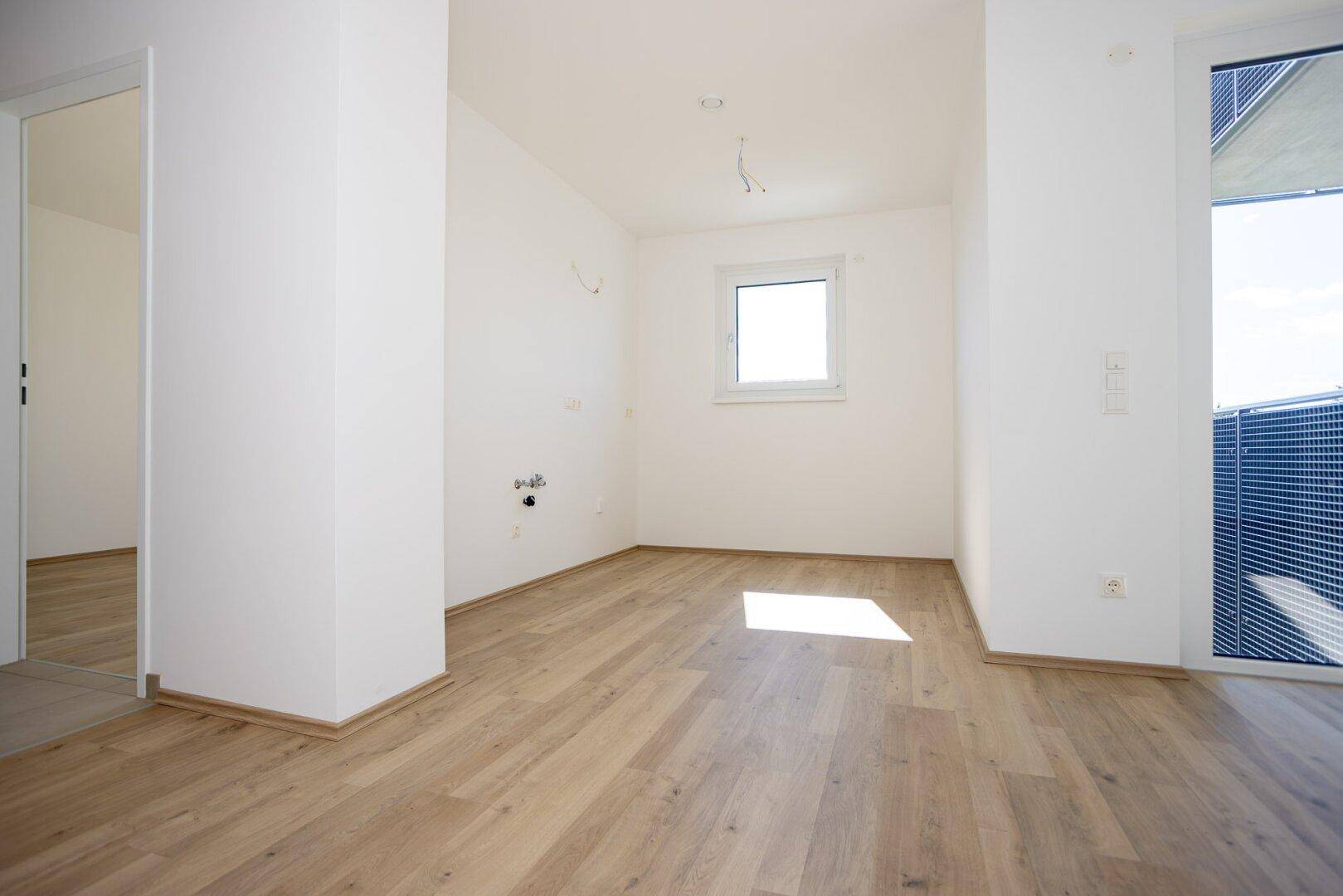 Helles Zimmer mit Holzboden und Fenster, bereit für die individuelle Gestaltung.
