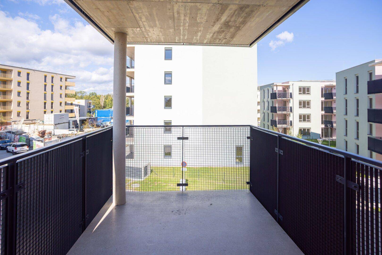 Moderner Balkon mit Metallgeländer und Blick auf die umliegenden Neubauten.