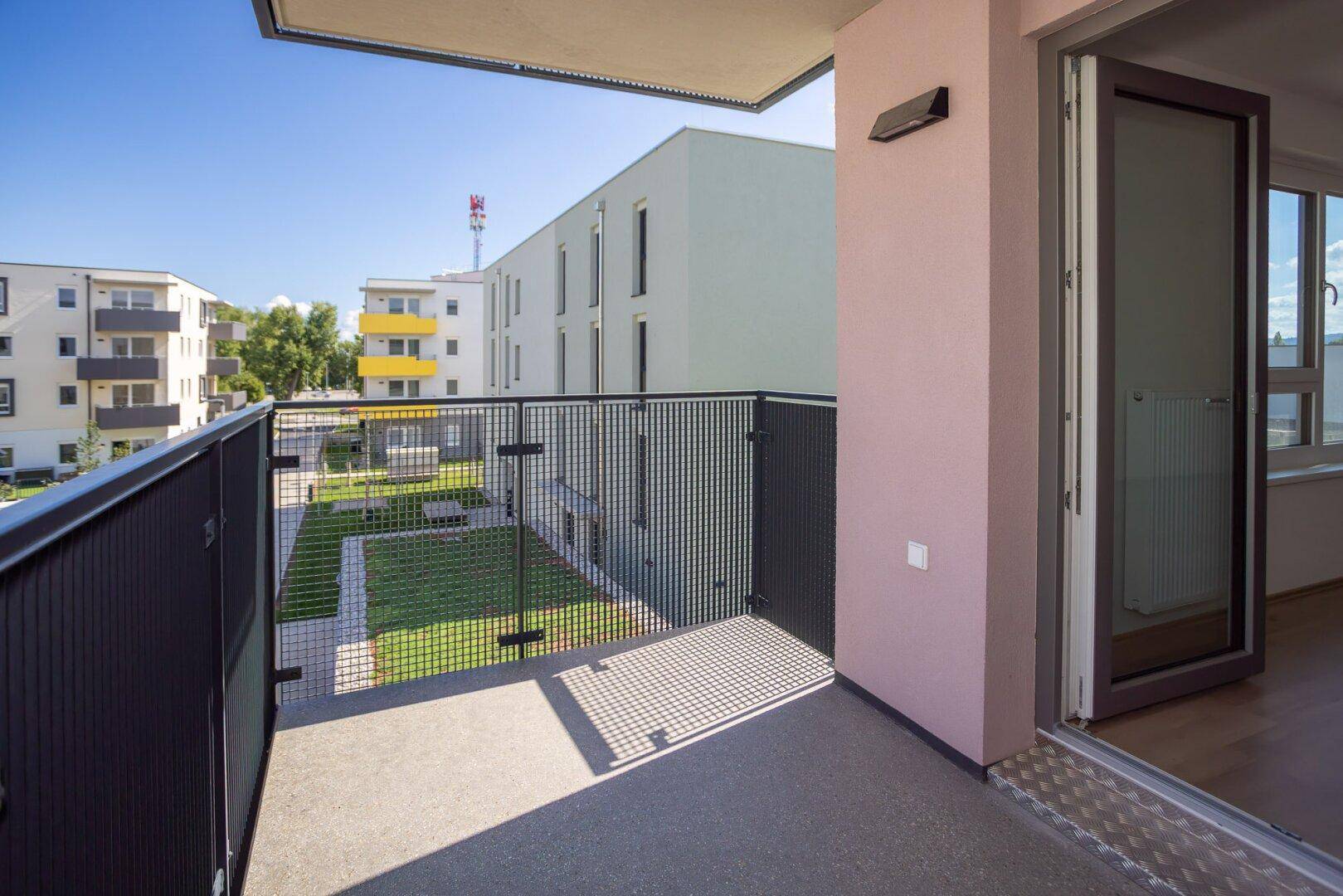 Balkon mit Blick auf die umliegenden Neubauten und den gepflegten Innenhof.