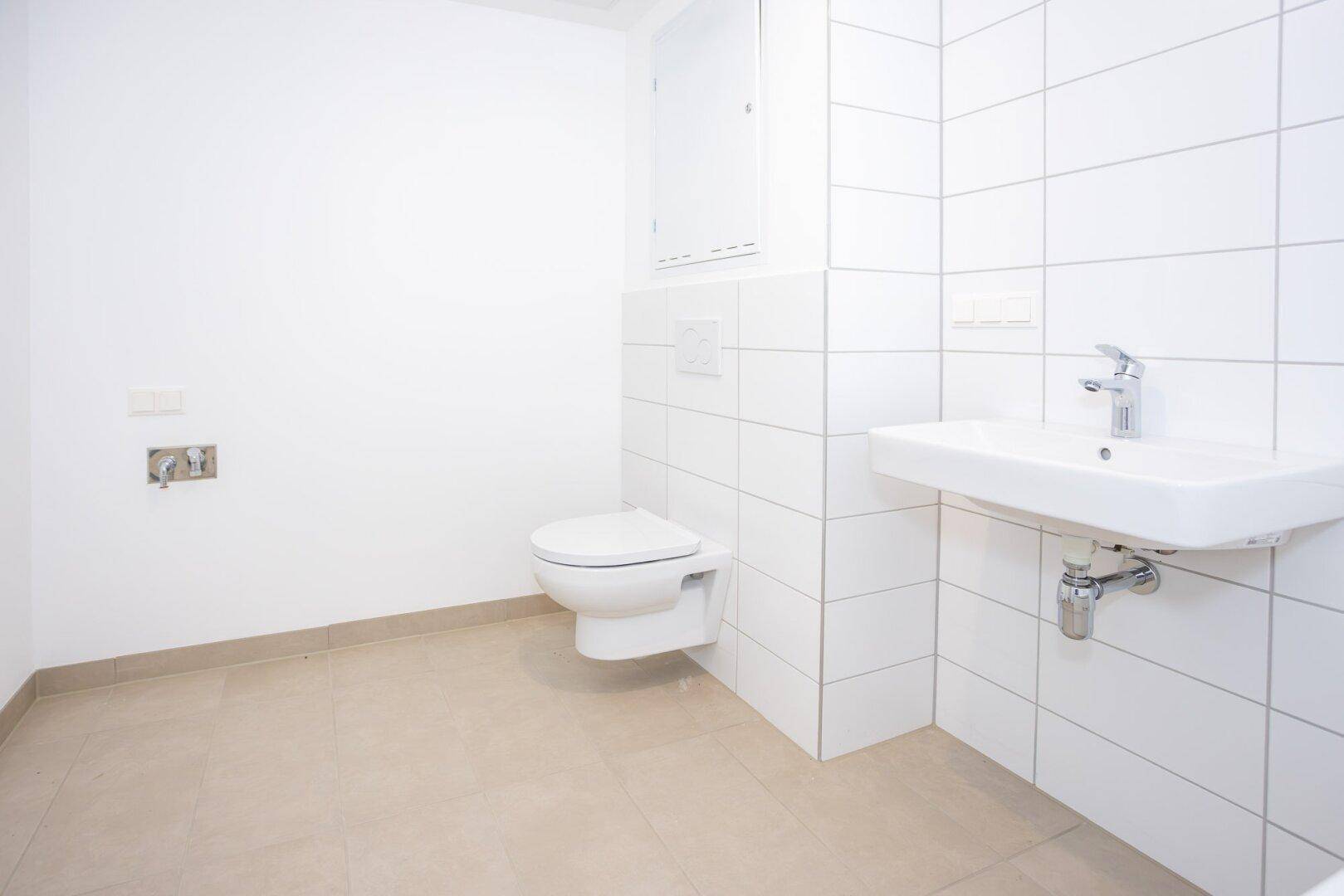 Helles Gäste-WC mit wandhängender Toilette und kleinem Waschbecken.
