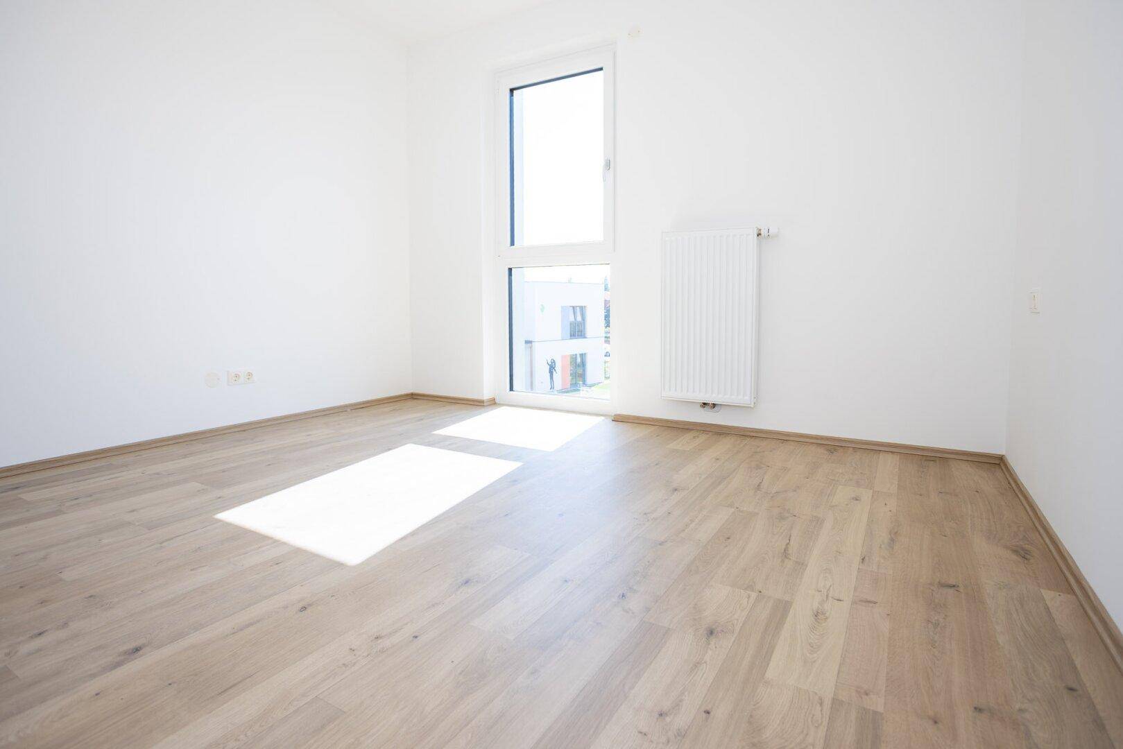 Geräumiges Schlafzimmer mit viel Tageslicht und neuwertigem Laminatboden.