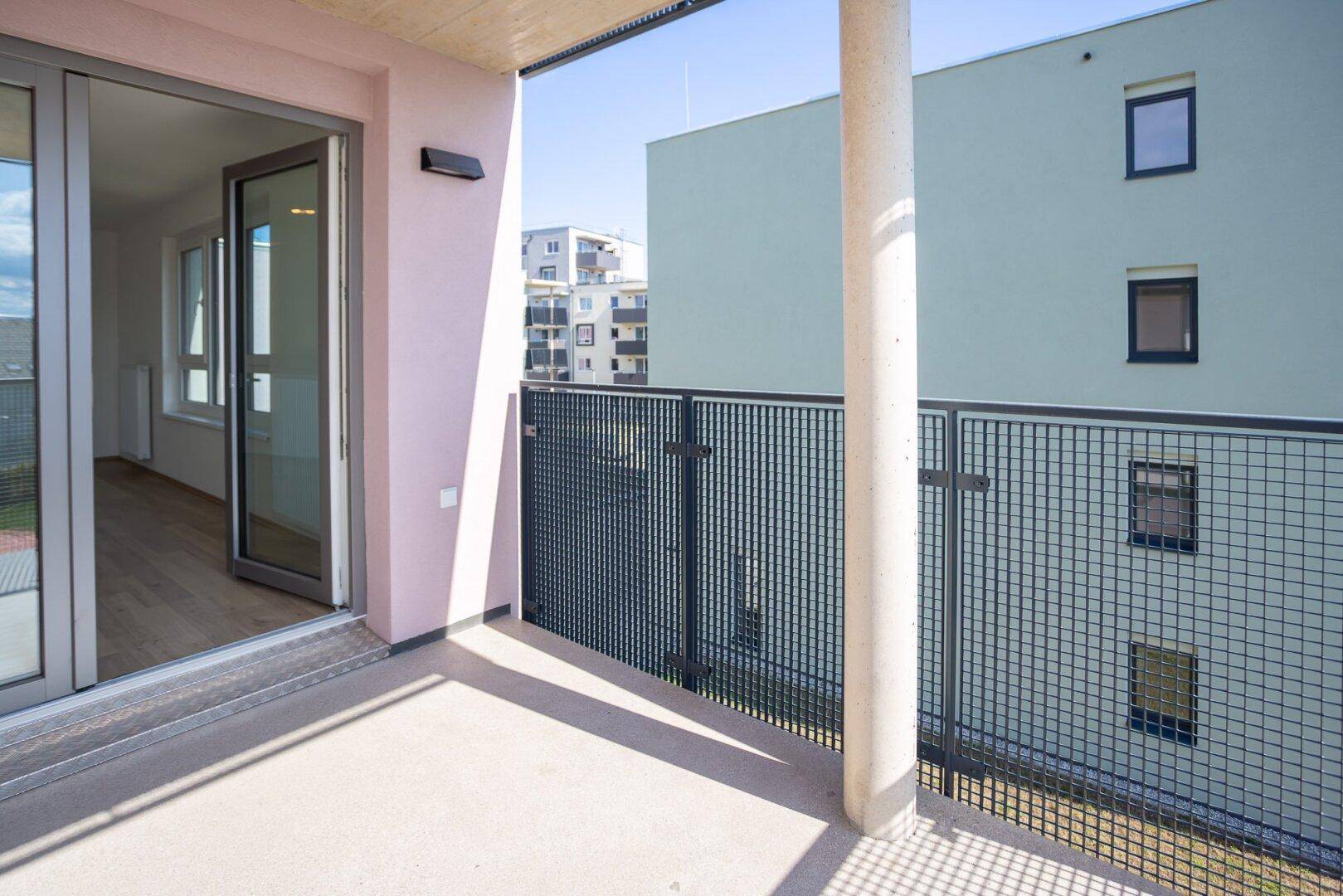 Geräumiger Balkon mit Metallgeländer und Blick auf die umliegenden Gebäude.