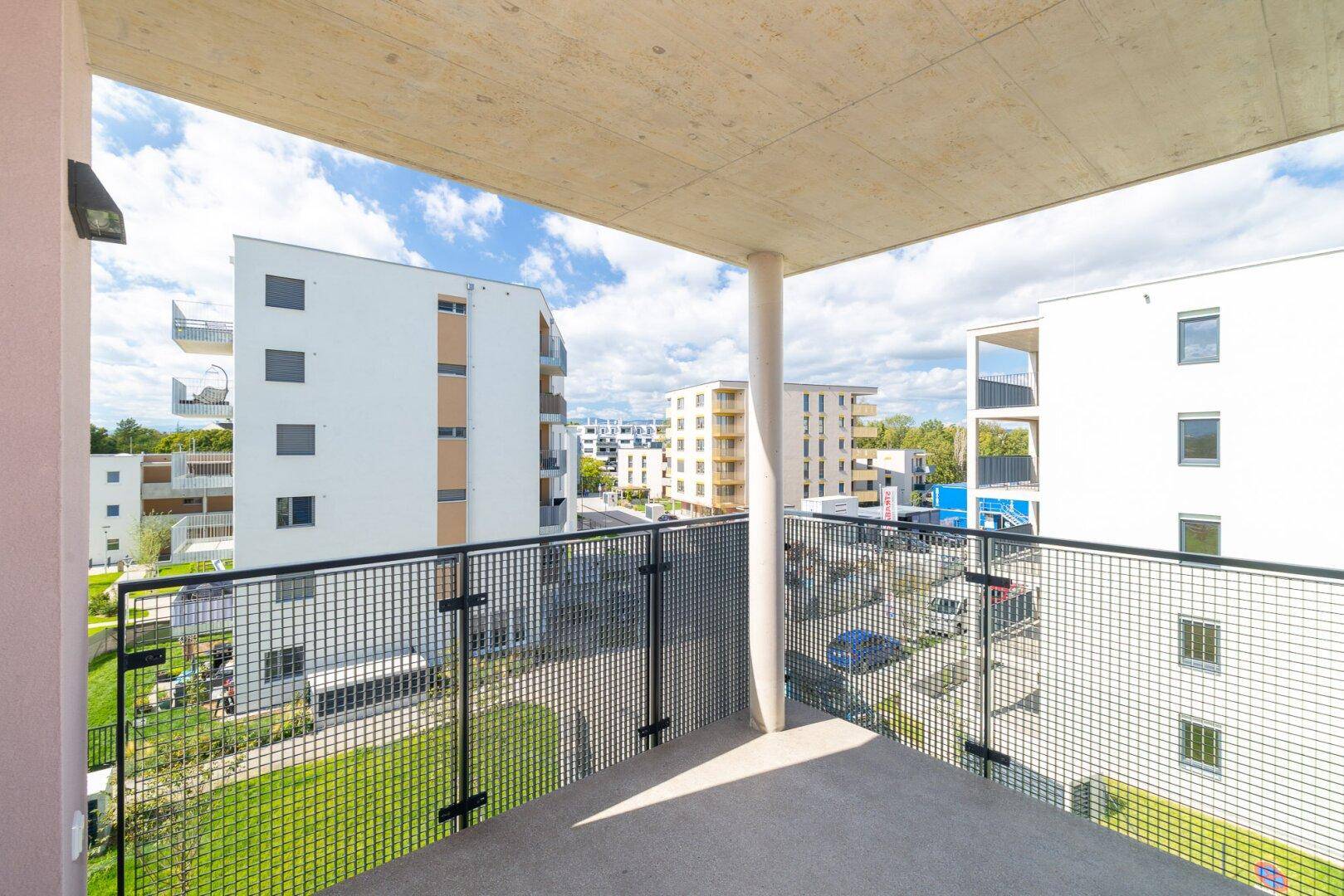 Geräumiger Balkon mit Metallgeländer und Blick auf die umliegenden modernen Wohngebäude.