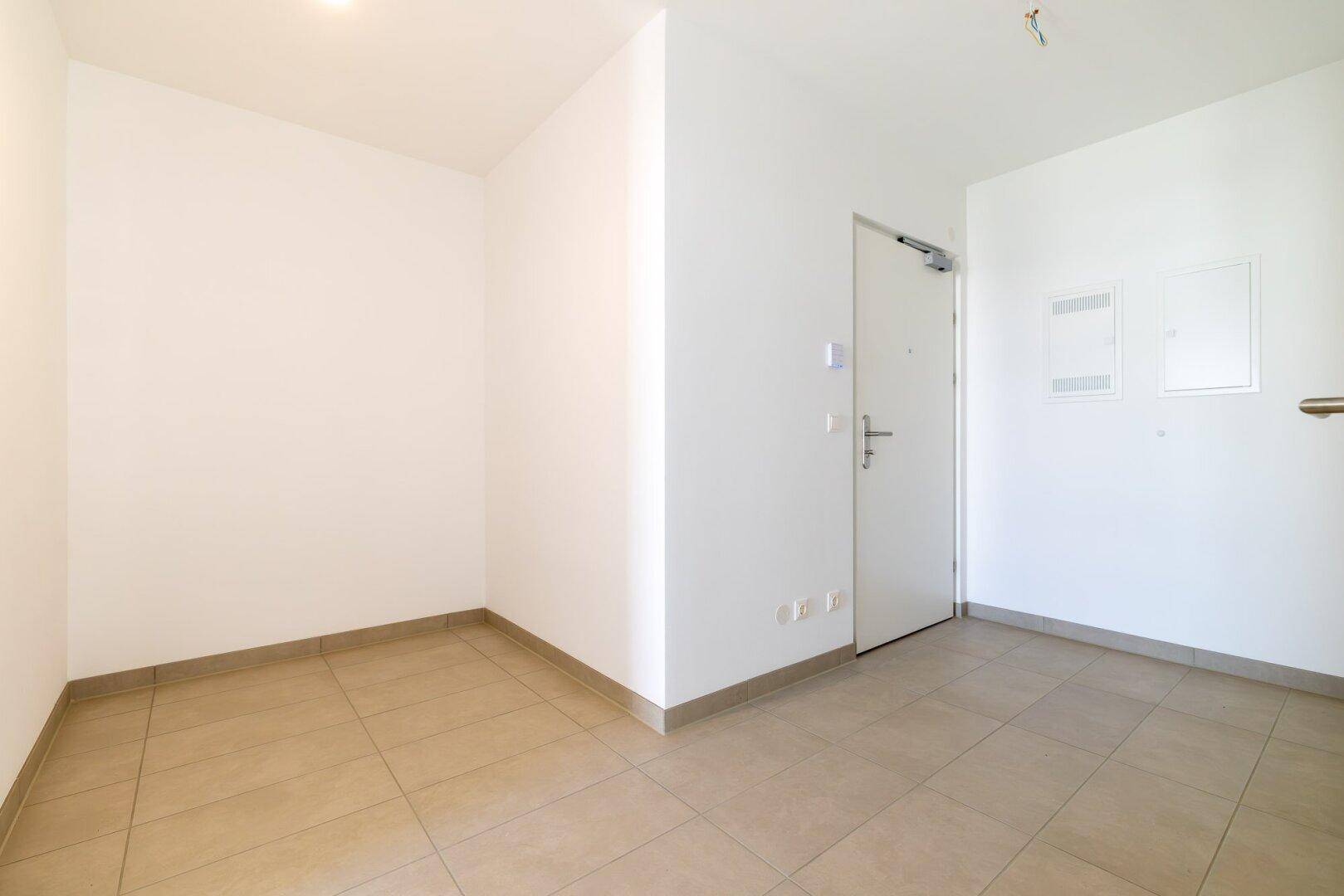 Heller Eingangsbereich mit beigefarbenen Fliesen und weißer Eingangstür, bietet viel Platz.