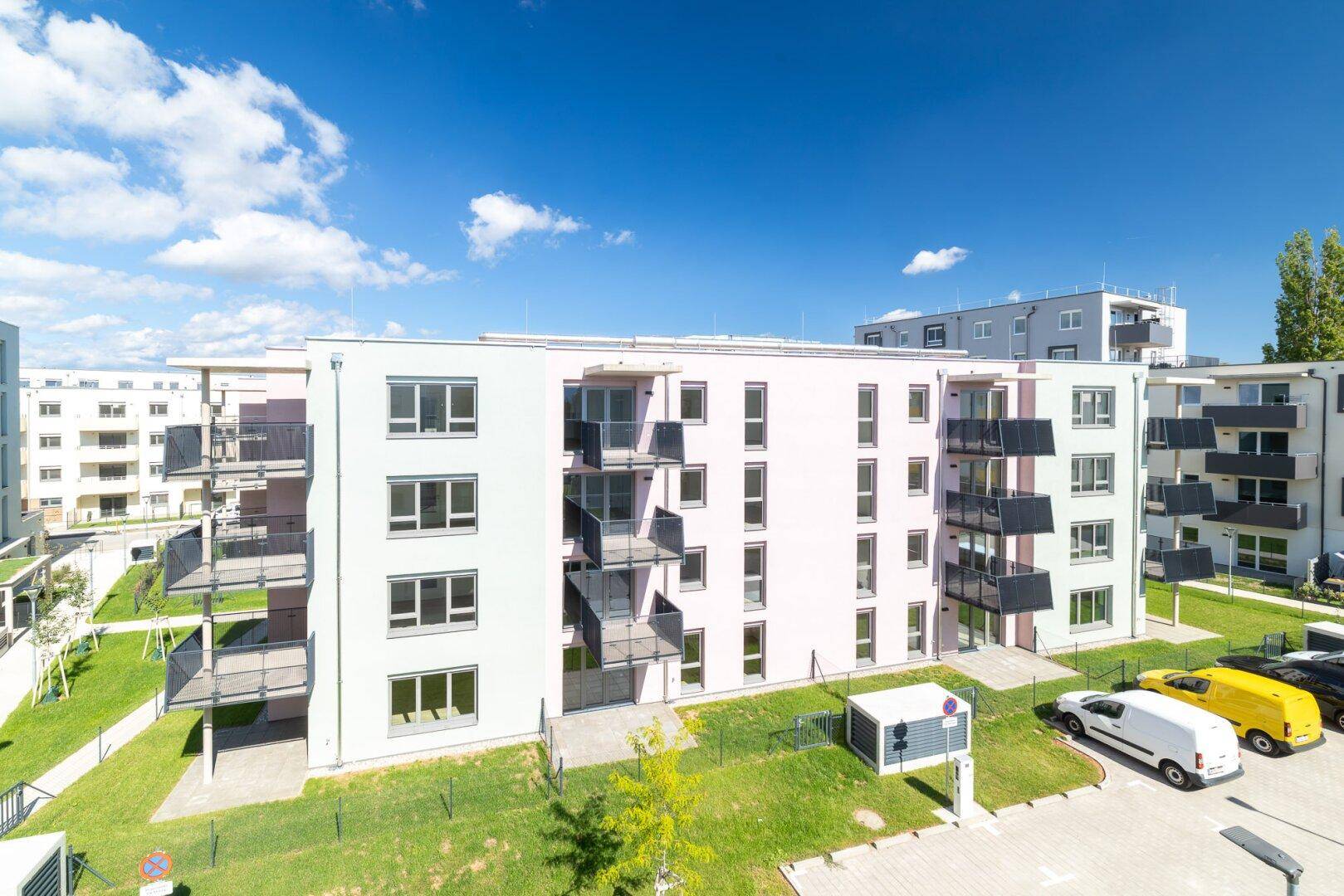 Moderne Wohnanlage mit hellen Fassaden, Balkonen und gepflegten Grünflächen im Außenbereich.