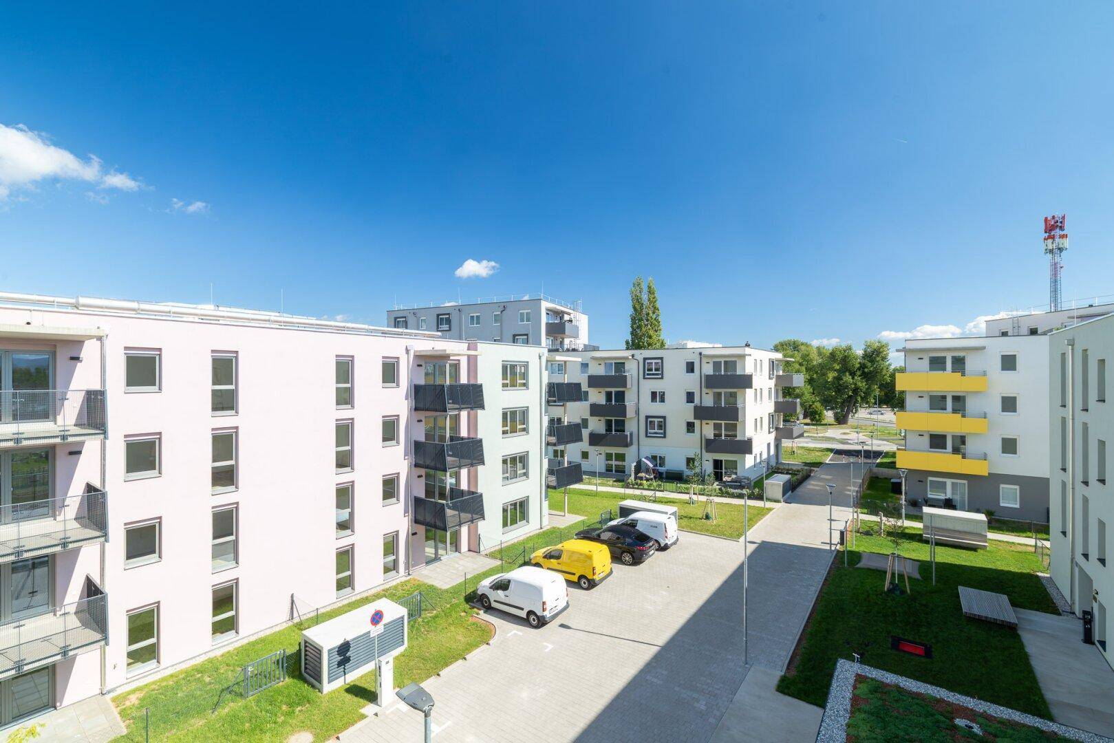 Überblick über die weitläufige, moderne Wohnanlage mit verschiedenen Gebäuden und Parkplätzen.