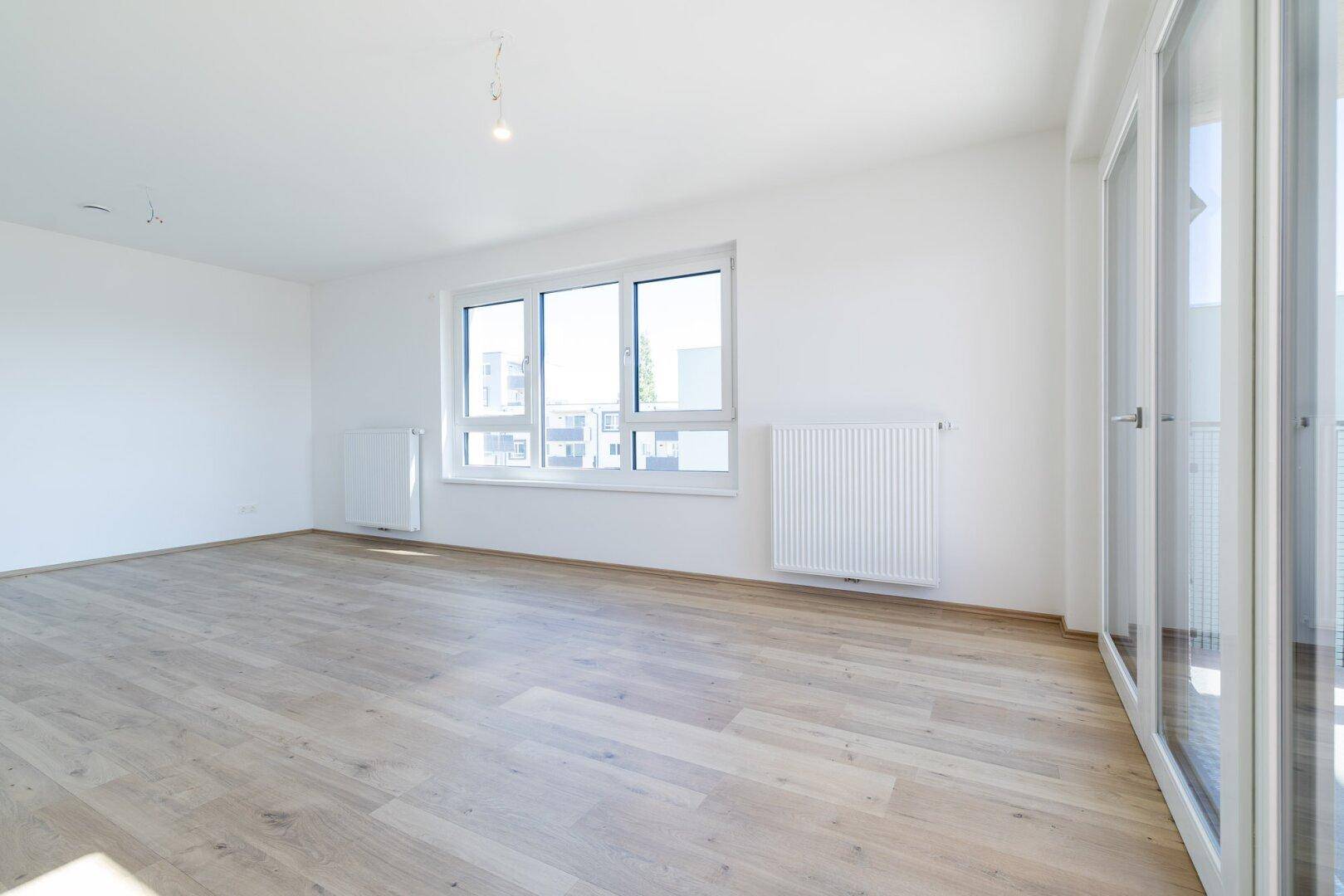 Heller, leerer Raum mit Laminatboden und großen Fenstern, ideal für individuelle Gestaltung.