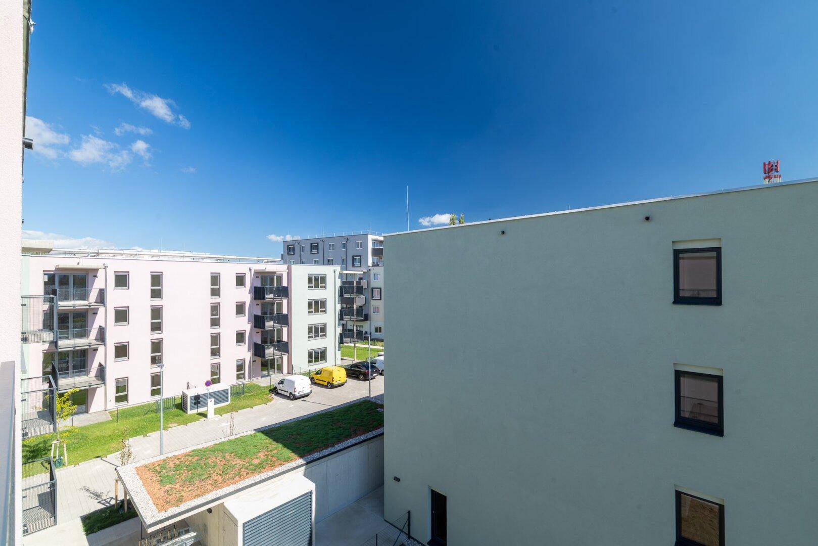 Überblick über die moderne Wohnanlage mit mehreren Gebäuden, begrünten Dächern und Parkplätzen.