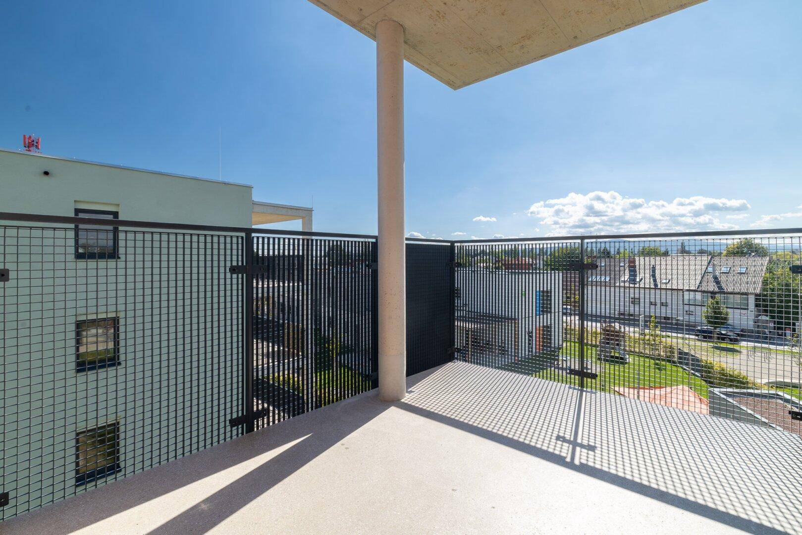Geräumiger Balkon mit Betonstütze und Gittergeländer, bietet weite Aussicht auf die Umgebung.
