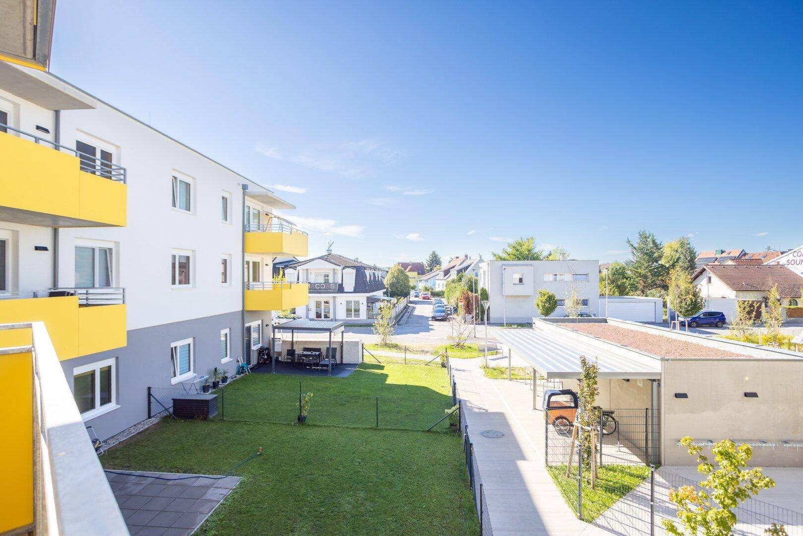 Blick auf die Wohnanlage mit gemeinschaftlichen Grünflächen, Carports und umliegenden Häusern.