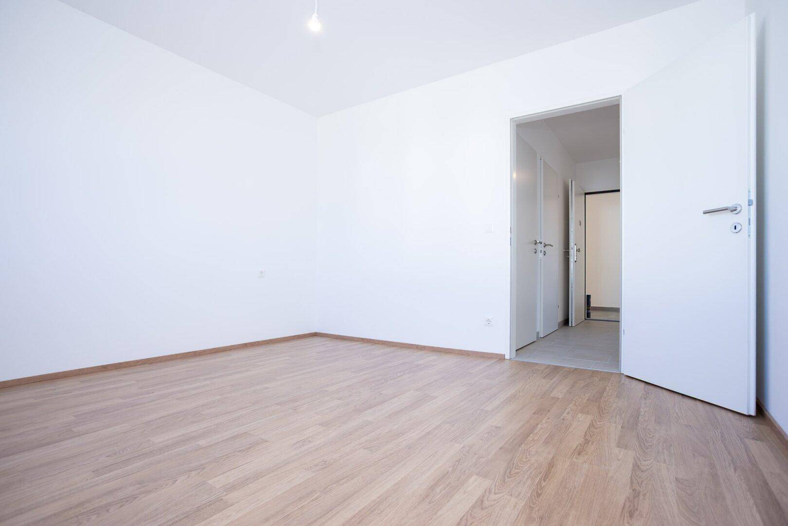 Helles Zimmer mit Laminatboden und weiß gestrichenen Wänden, ideal als Schlaf- oder Arbeitszimmer.