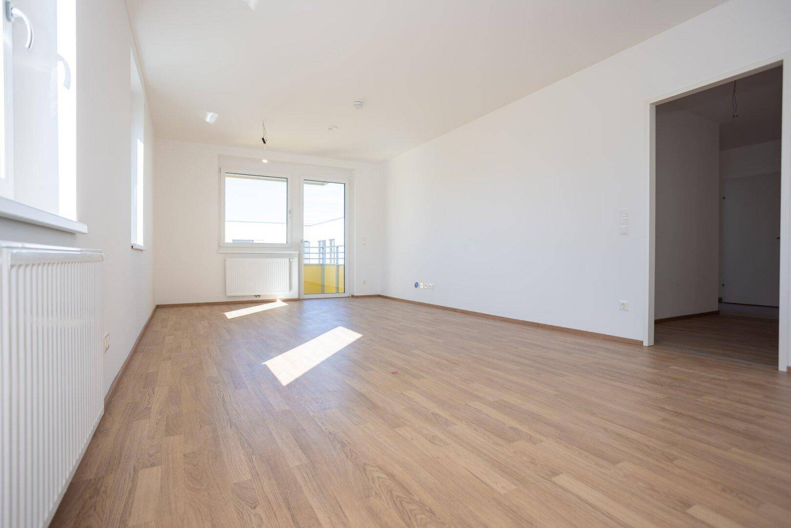 Geräumiges, helles Zimmer mit Laminatboden und großen Fenstern, bereit zur individuellen Gestaltung.