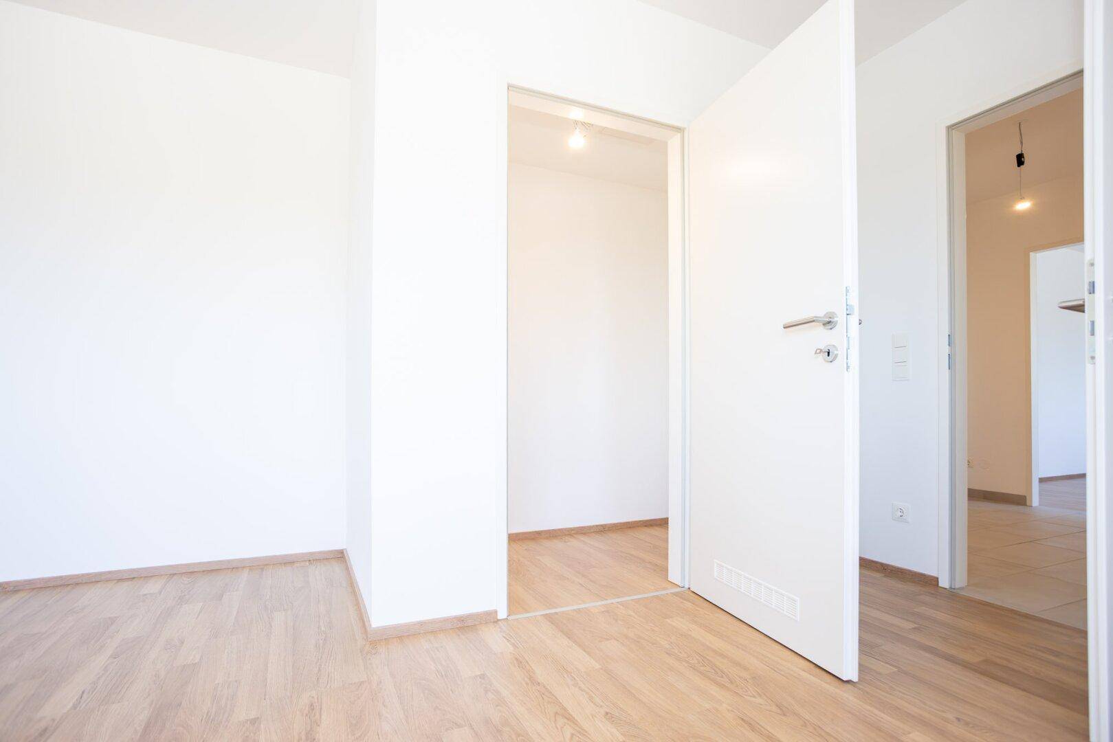 Heller Flur mit Laminatboden und mehreren Türen, die zu verschiedenen Zimmern führen.