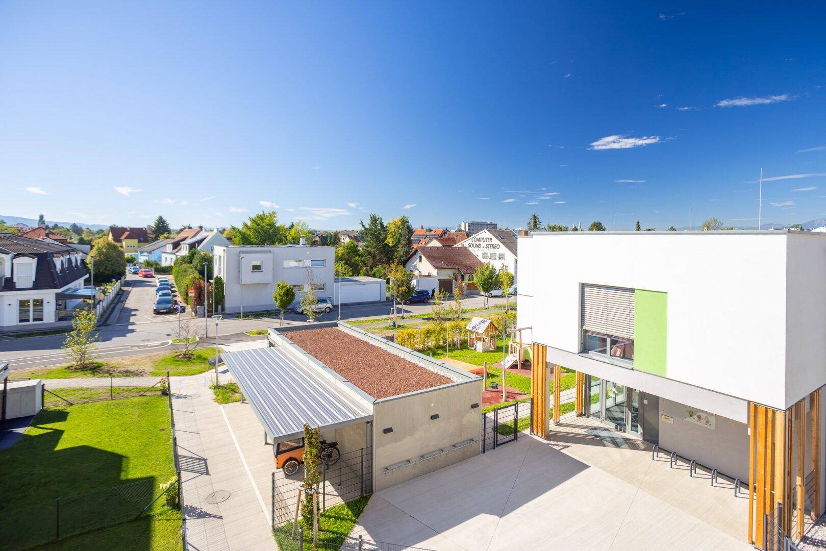 Weitläufige Außenansicht der Wohnanlage mit Spielplatz und Carport.