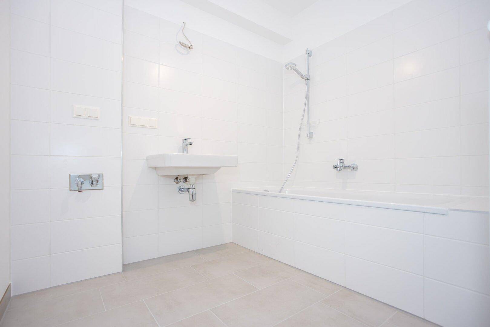 Modernes Badezimmer mit Badewanne, Waschbecken und weißen Fliesen.