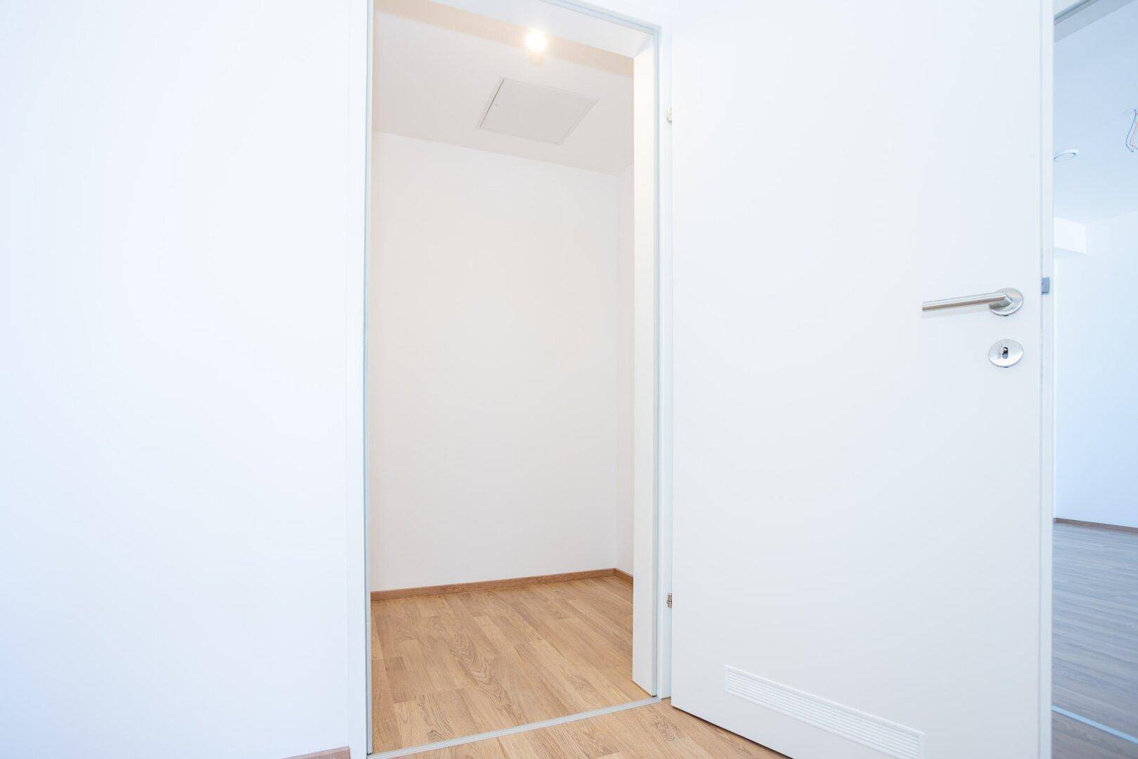 Kleiner, leerer Abstellraum mit Laminatboden und weiß gestrichenen Wänden.