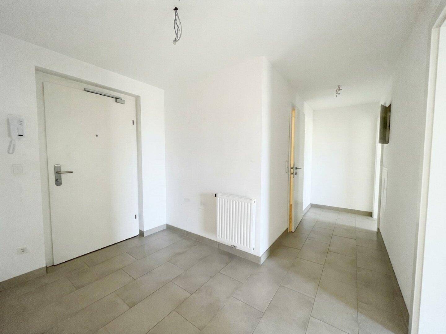 Geräumiger Eingangsbereich mit Fliesenboden und weiß gestrichenen Wänden, bietet Platz für Garderobe.