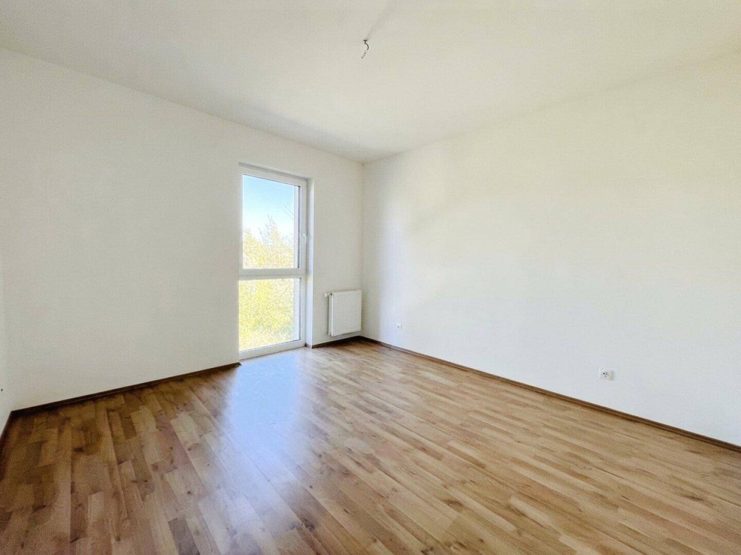 Geräumiges Schlafzimmer mit Laminatboden und hellen Wänden, bietet viel Platz für individuelle Einrichtung.