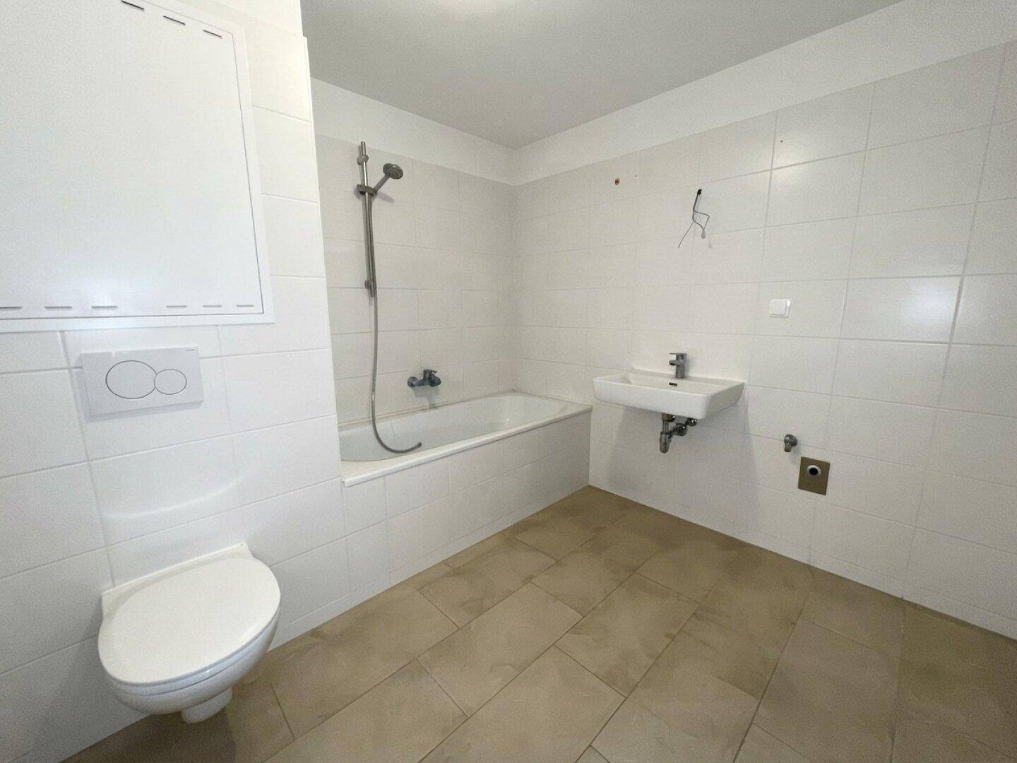 Helles Badezimmer mit weißen Fliesen, Badewanne, Toilette und Waschbecken, in gutem Zustand.