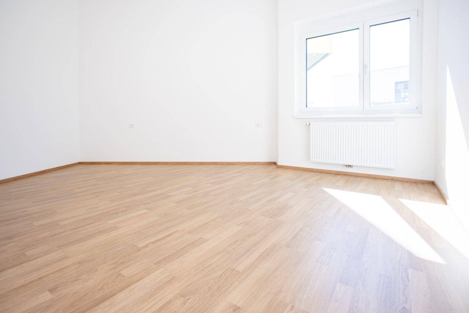 Helles Schlafzimmer mit Laminatboden und weiß gestrichenen Wänden, bietet eine angenehme Atmosphäre.