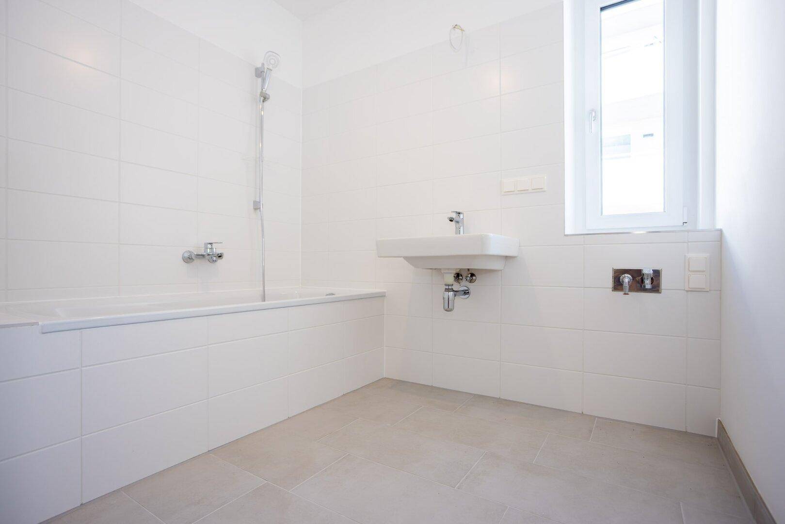 Modernes Badezimmer mit Badewanne, Waschbecken und weißen Fliesen.